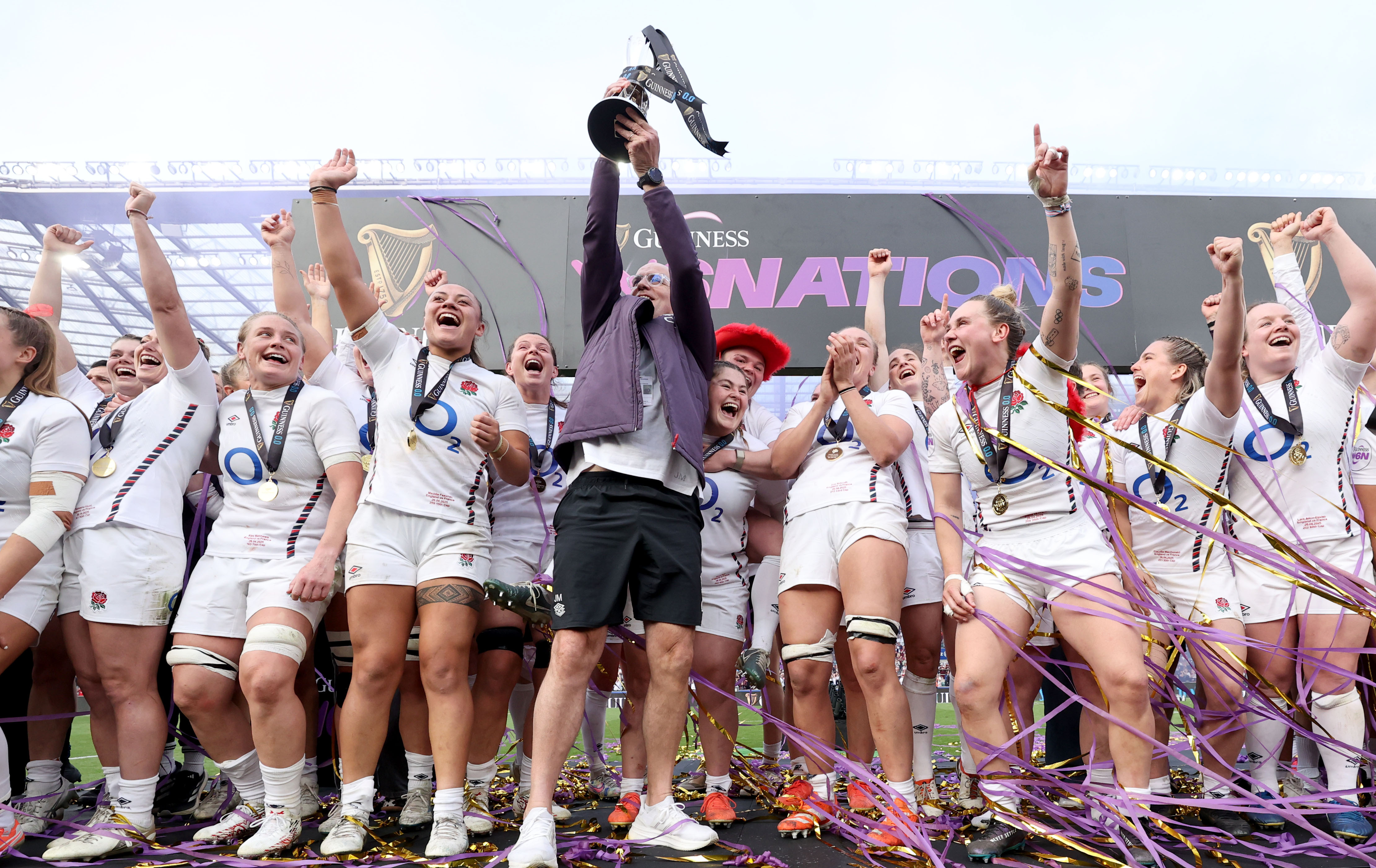 John Mitchell lifts the 2025 Championship trophy, surrounded by the Red Roses squad.