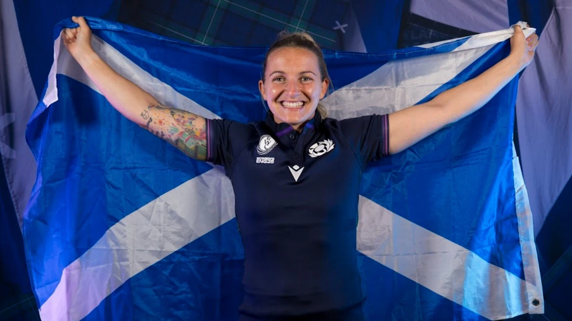 Chloe Rollie, in Rugby World Cup kit, holds up Scotland's Saltire flag ahead of the 2025 tournament. 