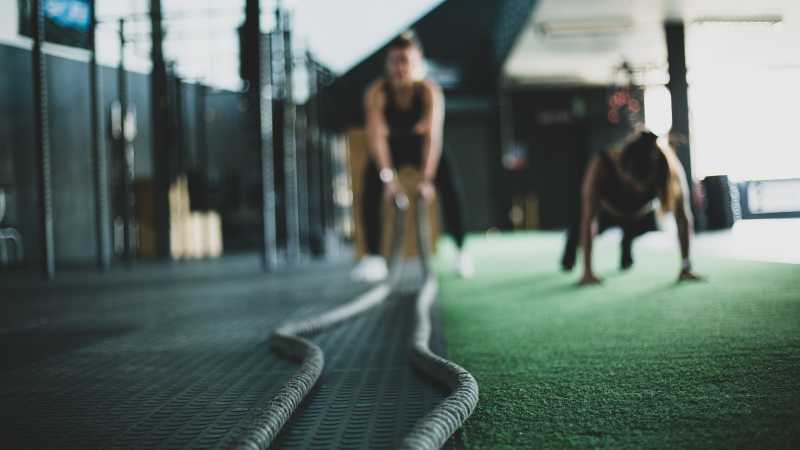 Woman exercising with gym battle ropes