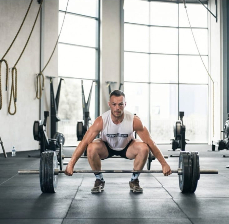 A man holding a weighted barbell on the floor.