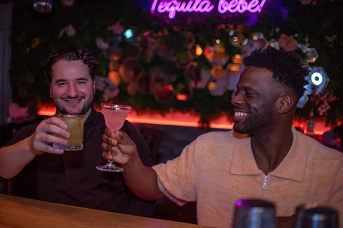 Two men enjoying cocktails at a bar