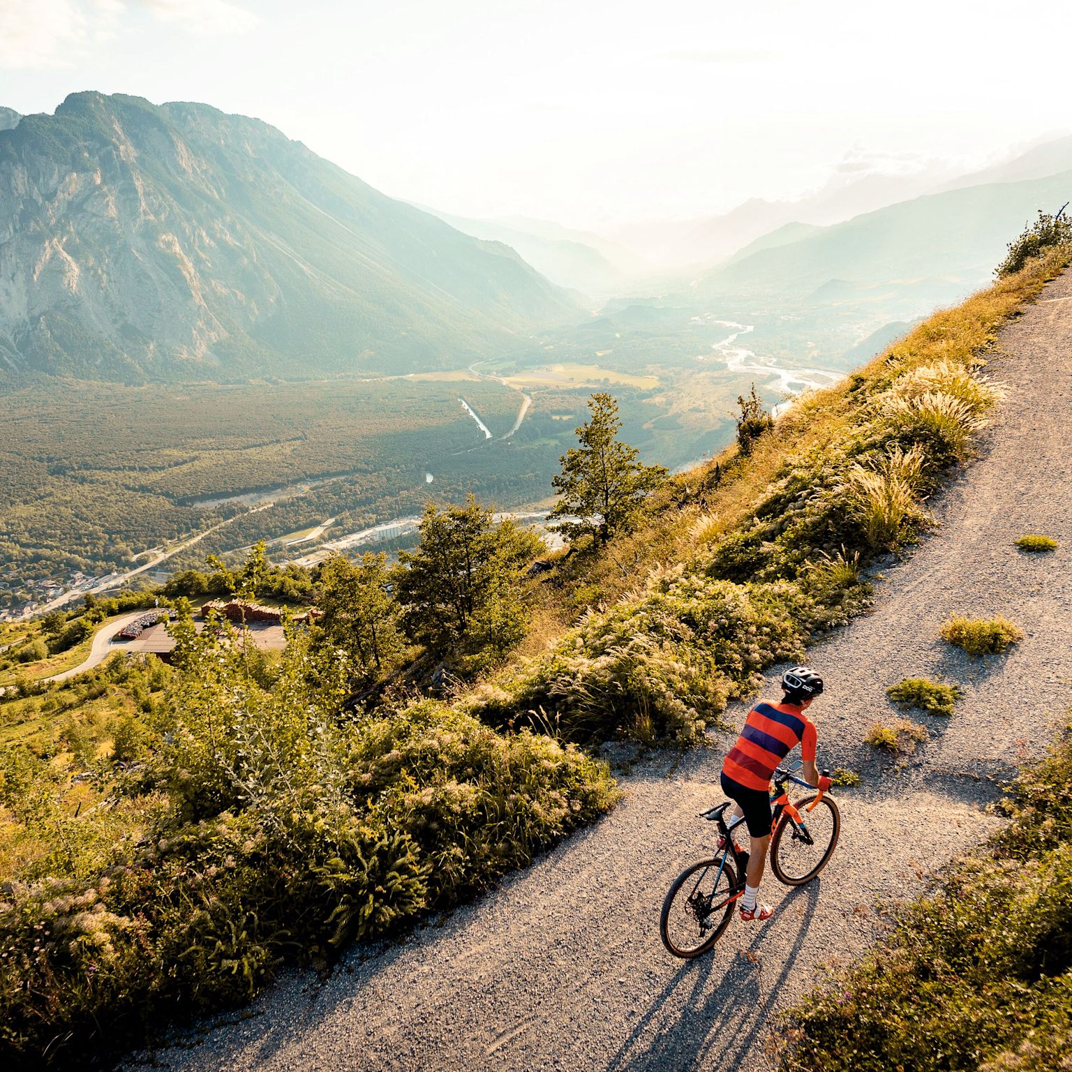 Person gravel biking on a mountain trail above Leuk with view over the Rhône Valley, Valais, Switzerland