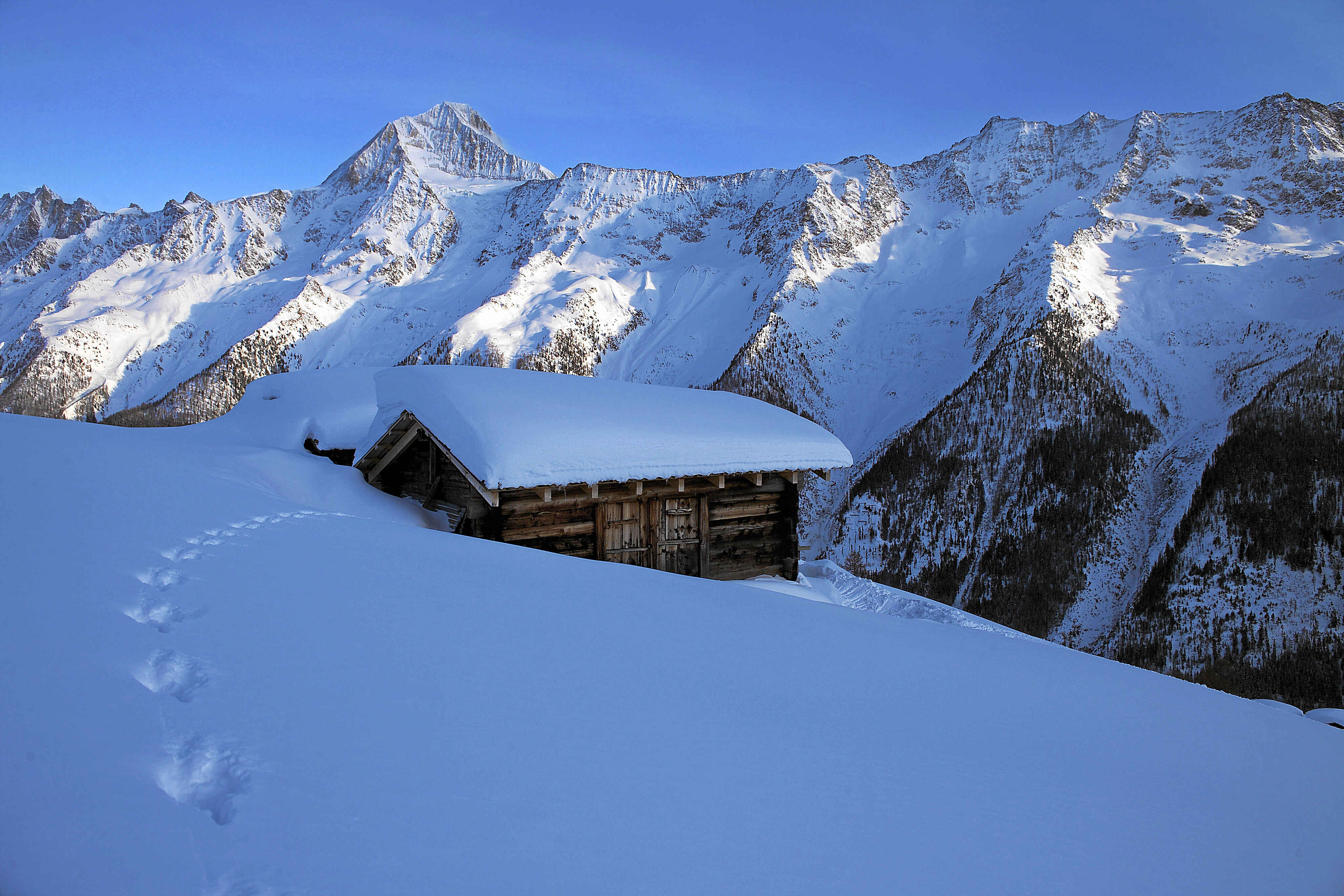 Eingeschneiter Weiler unterhalb der Hockenalp mit dem Nesthorn und dem Bietschhorn im Hintergrund. 