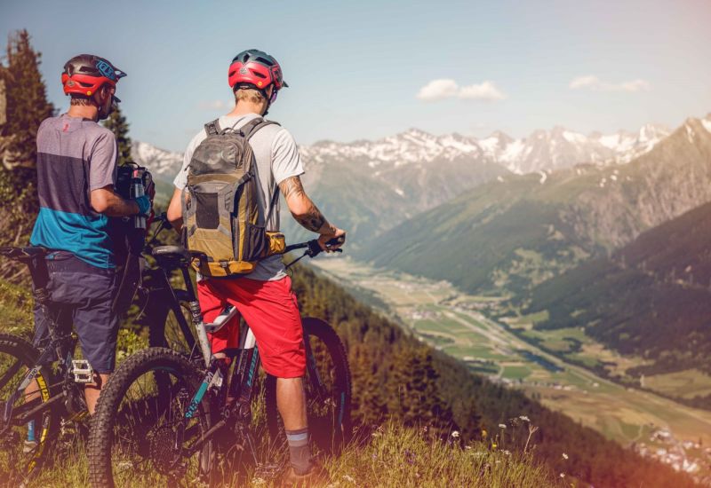 2 mountain bikers take a break to observe the Valais plain during their mountain bike ride. Valais, Switzerland