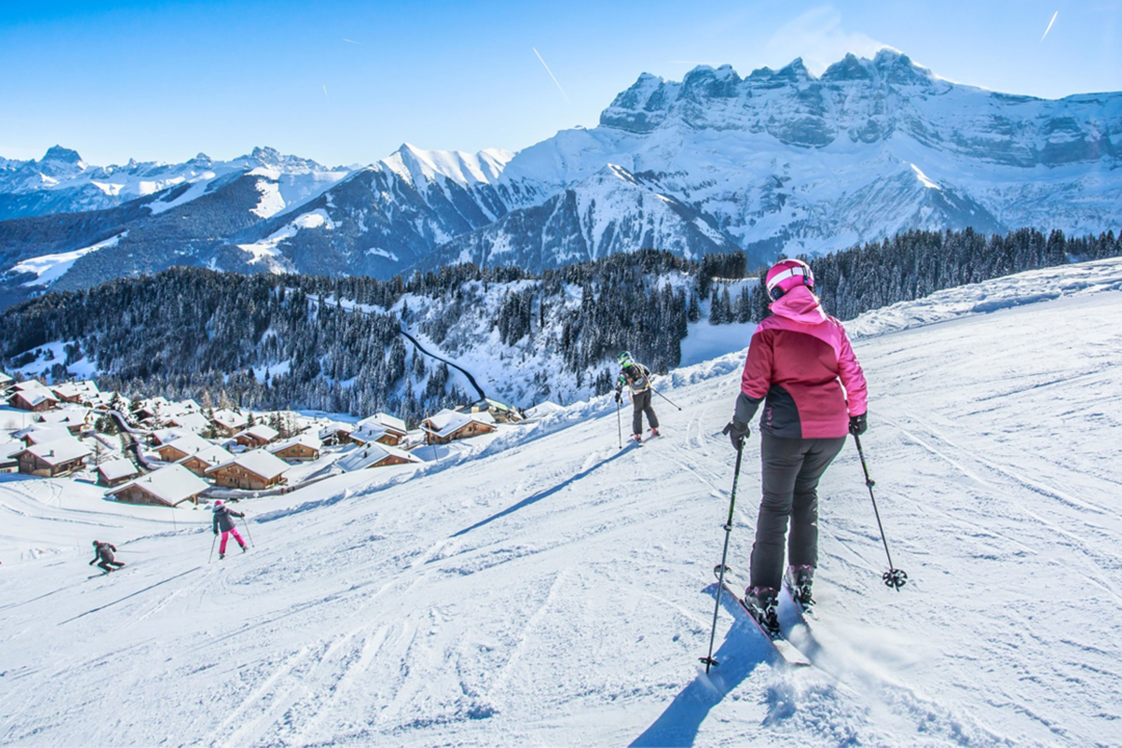 Eine Skifahrerin fährt die Piste Sépaya in Morgins hinunter, mit den majestätischen Dents du Midi im Hintergrund.