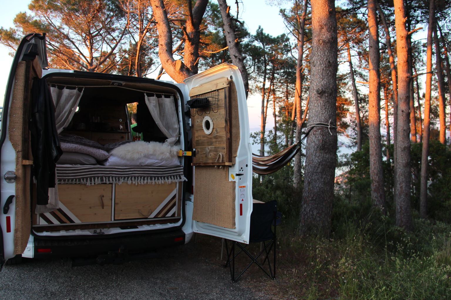 Van renové en camping car devant une forêt à la tombée de la nuit