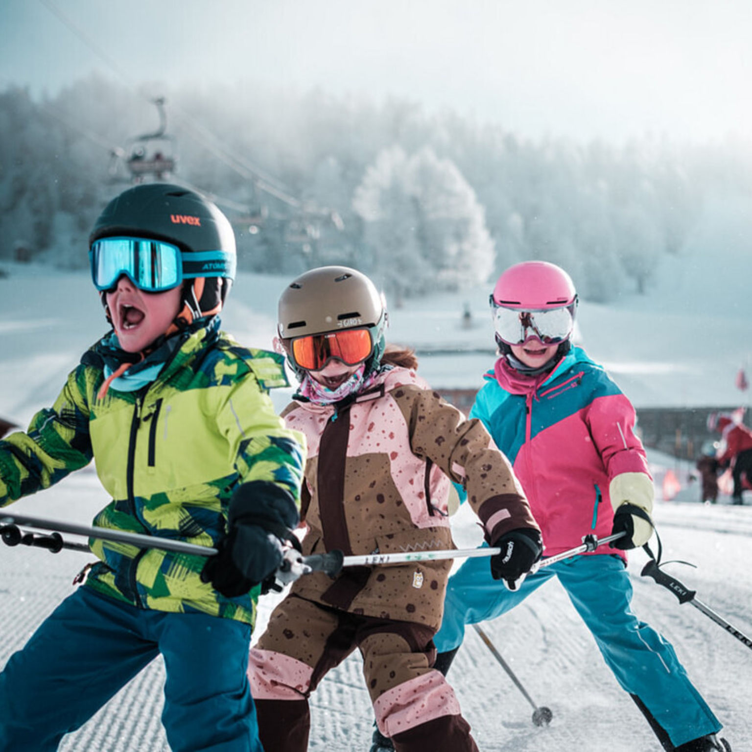 Drei Kinder fahren fröhlich Ski im Skigarten Talentschmiede auf der Hannigalp in Grächen, ideal für das sichere Skifahrenlernen.