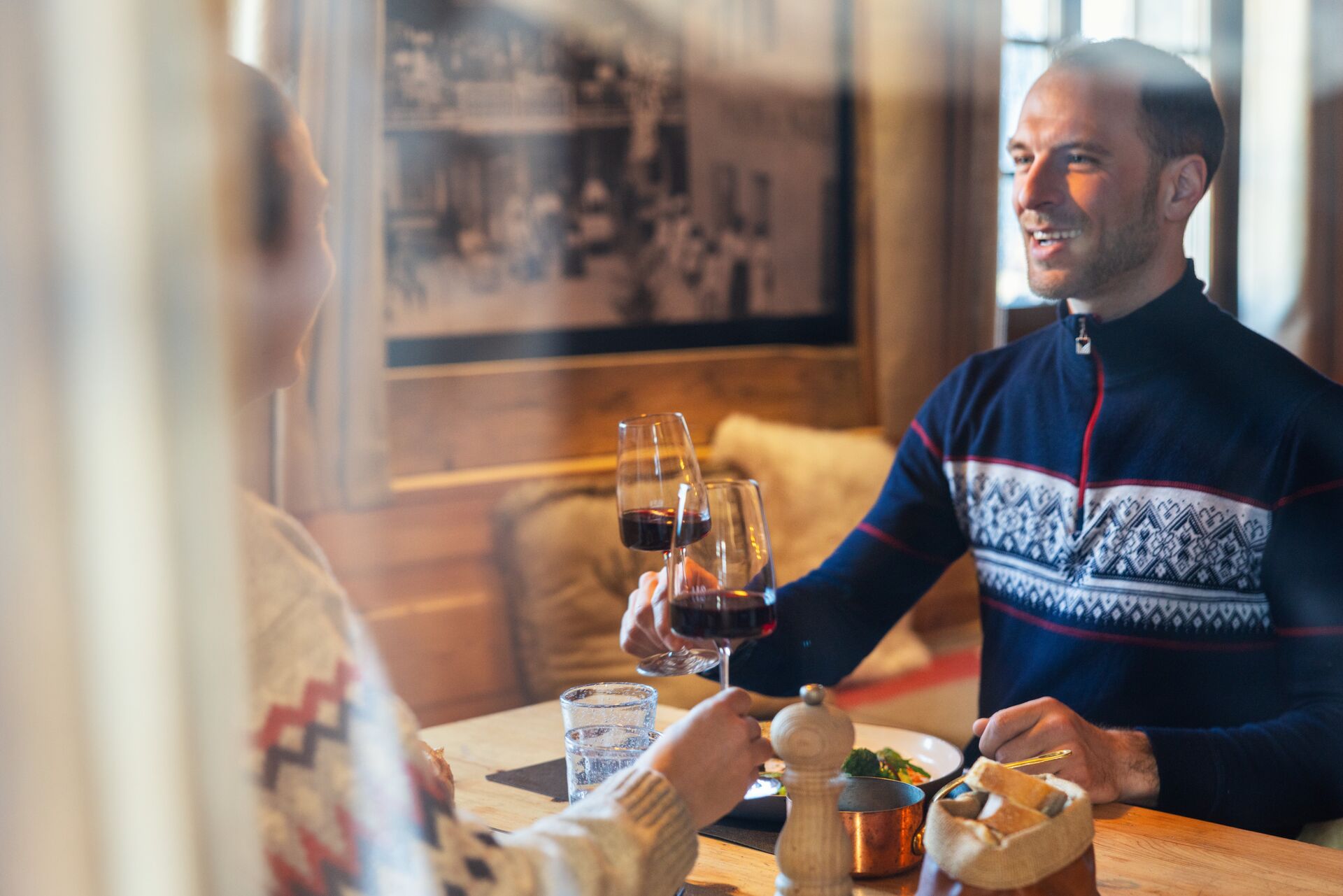 Un couple trinque au vin rouge dans un restaurant rustique à Champéry