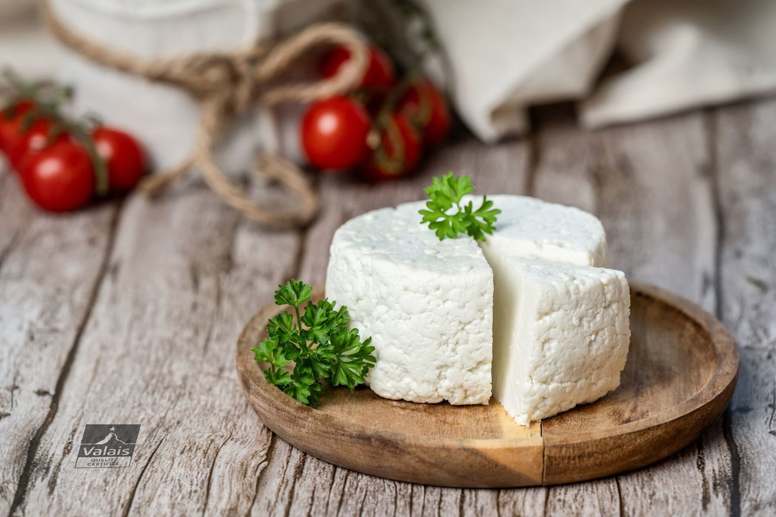 Walliser Ziger auf einem Holzbrett mit Petersilie und Tomaten