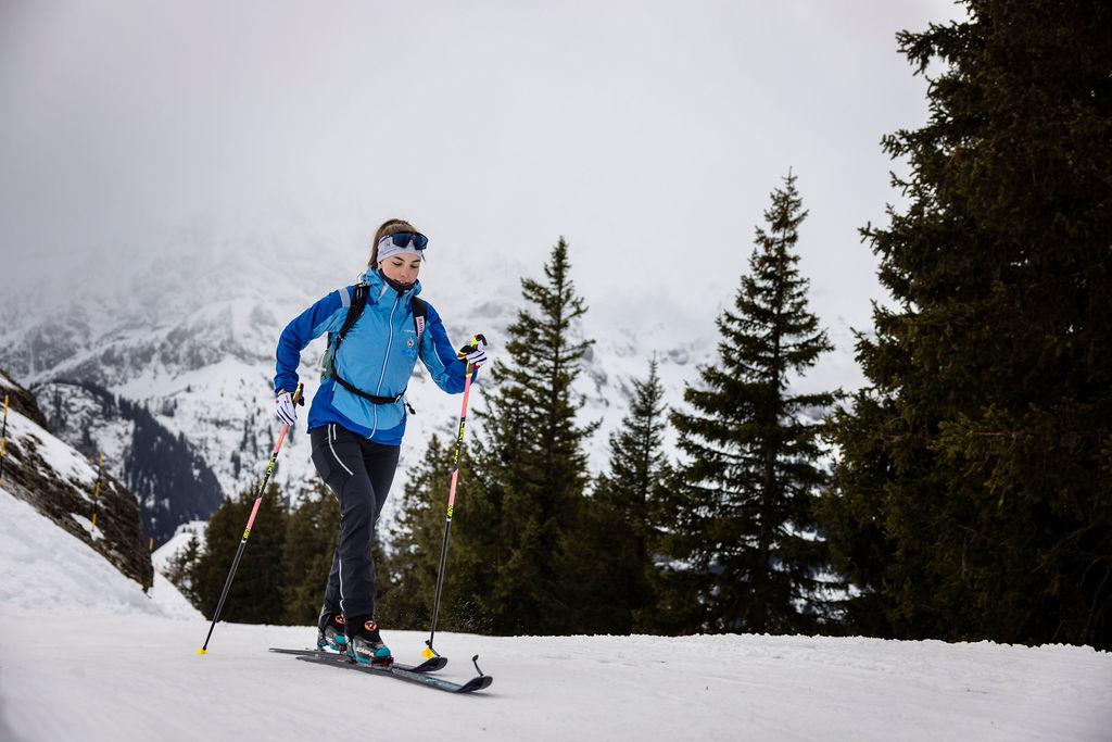 Woman ski mountaineering in Valais, Switzerland, with touring skis and poles on a snowy mountain slope. Winter, Valais, Switzerland.