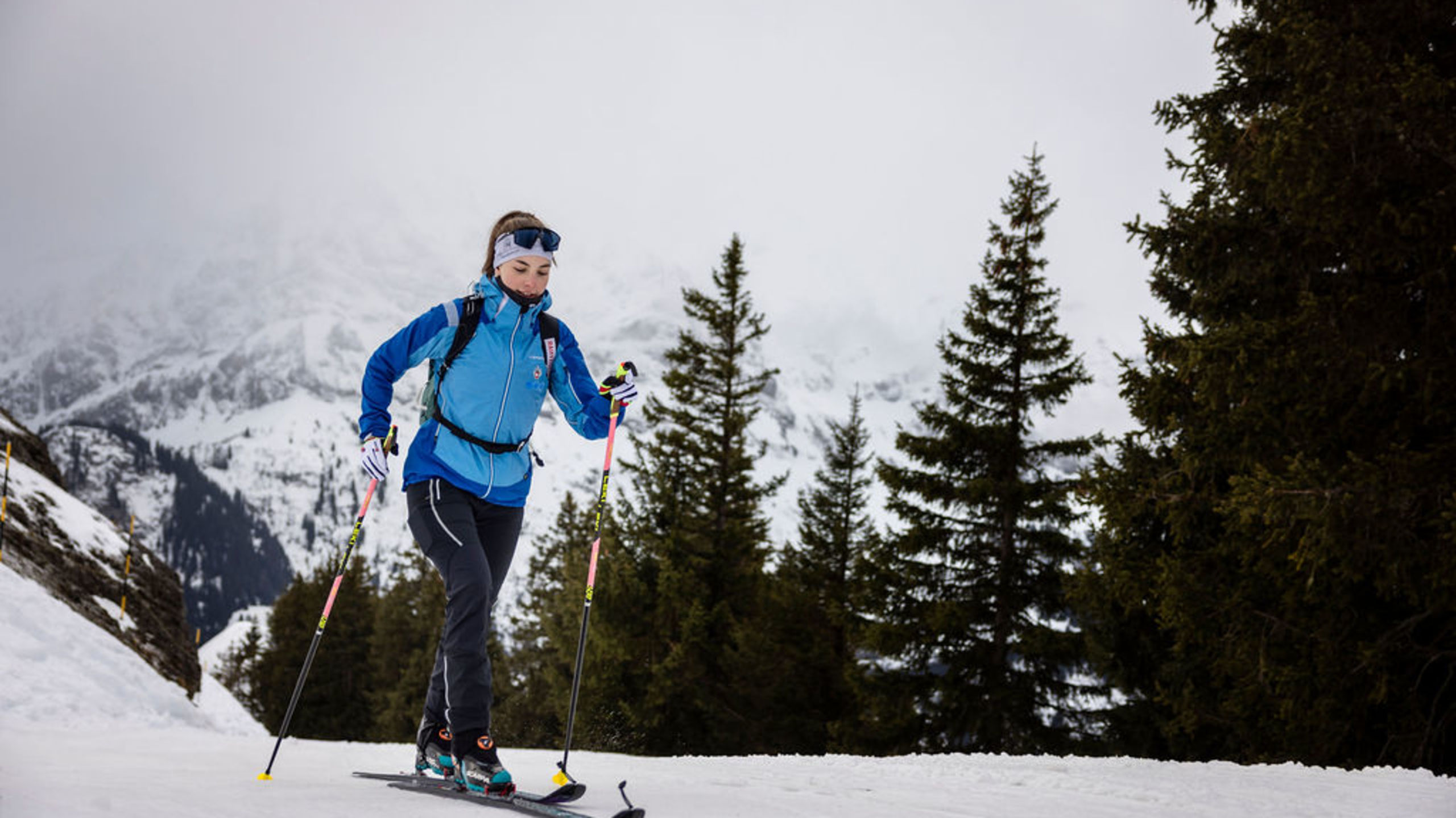Woman ski mountaineering in Valais, Switzerland, with touring skis and poles on a snowy mountain slope. Winter, Valais, Switzerland.