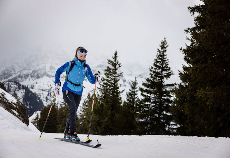 Woman ski mountaineering in Valais, Switzerland, with touring skis and poles on a snowy mountain slope. Winter, Valais, Switzerland.