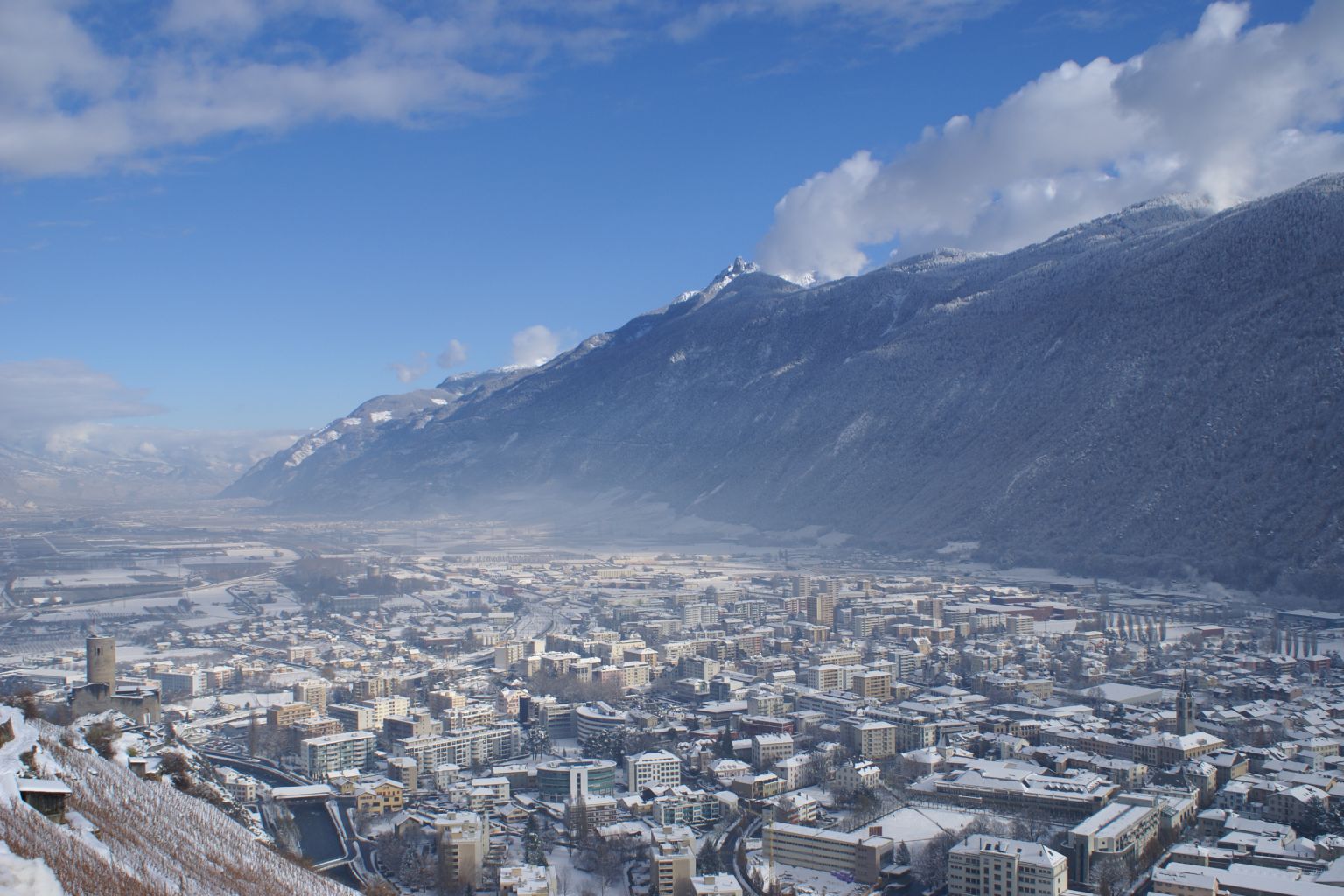 Vue sur la ville de Martigny enneigée depuis la route de la Forclaz en hiver. Valais. Suisse