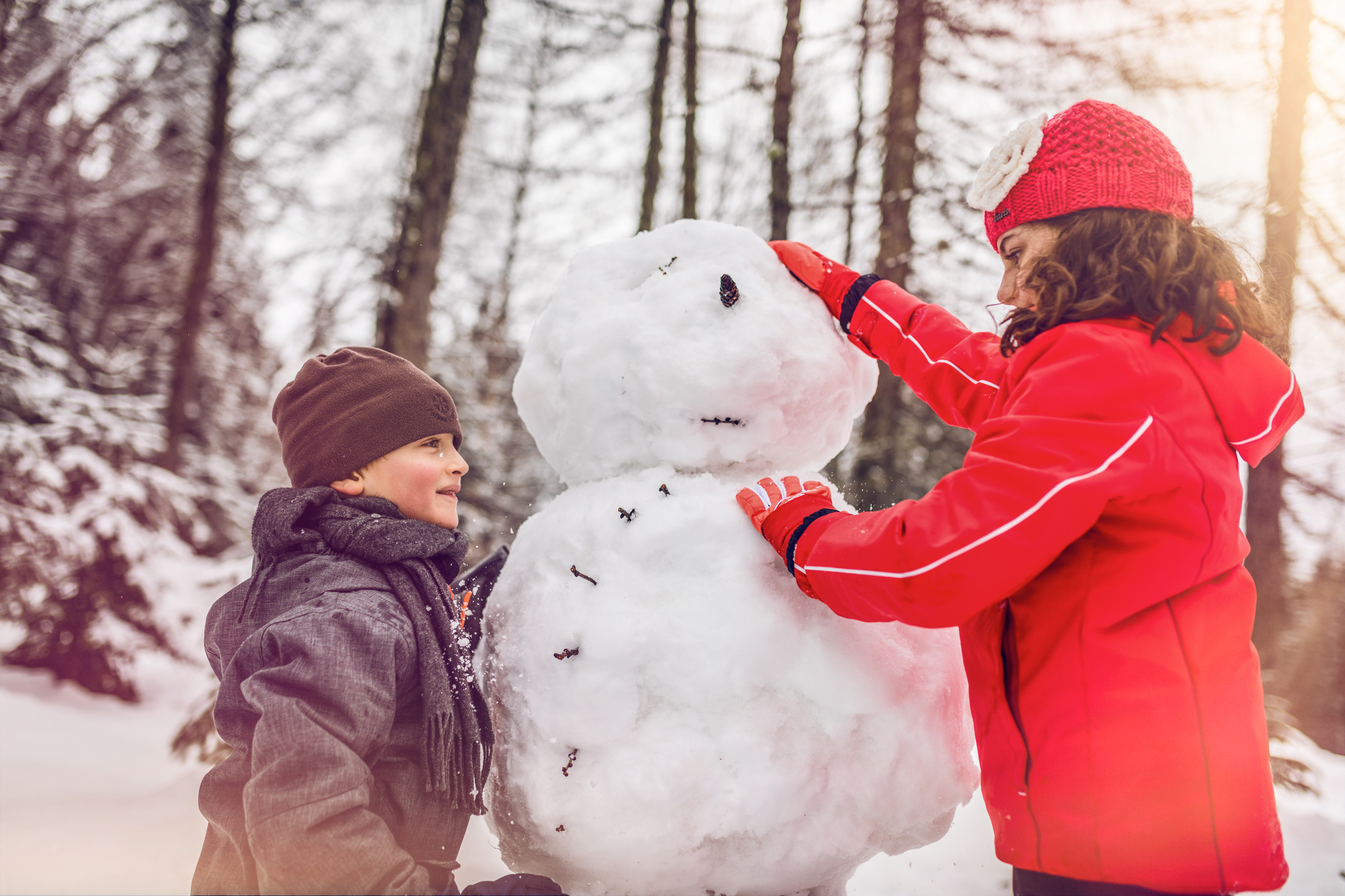 Kinder beim Schneemann bauen, Winter im Wallis, Crans-Montana, Familienferien, Schweiz