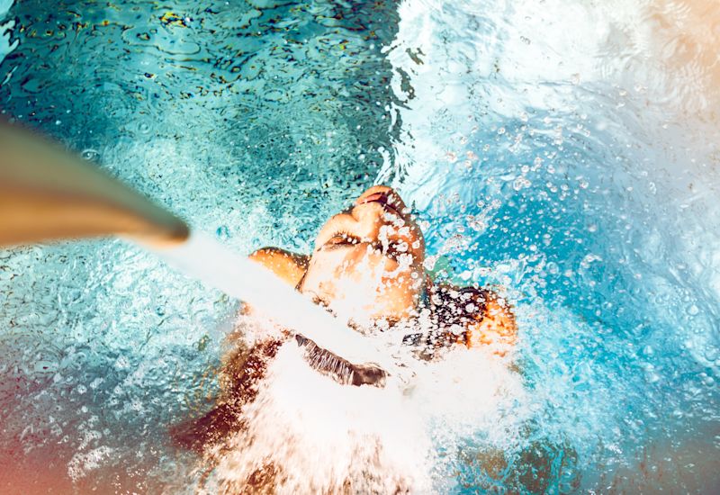 Ein Mädchen unter einem Jet aus den Bädern von Saillon. Wallis, Schweiz.