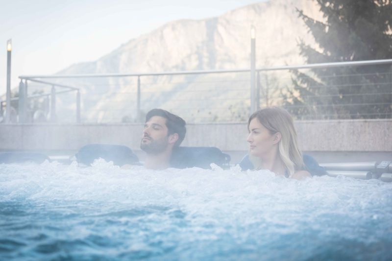 Deux personnes profitent des massages à bulles des bains à Leukerbad. Valais, Suisse