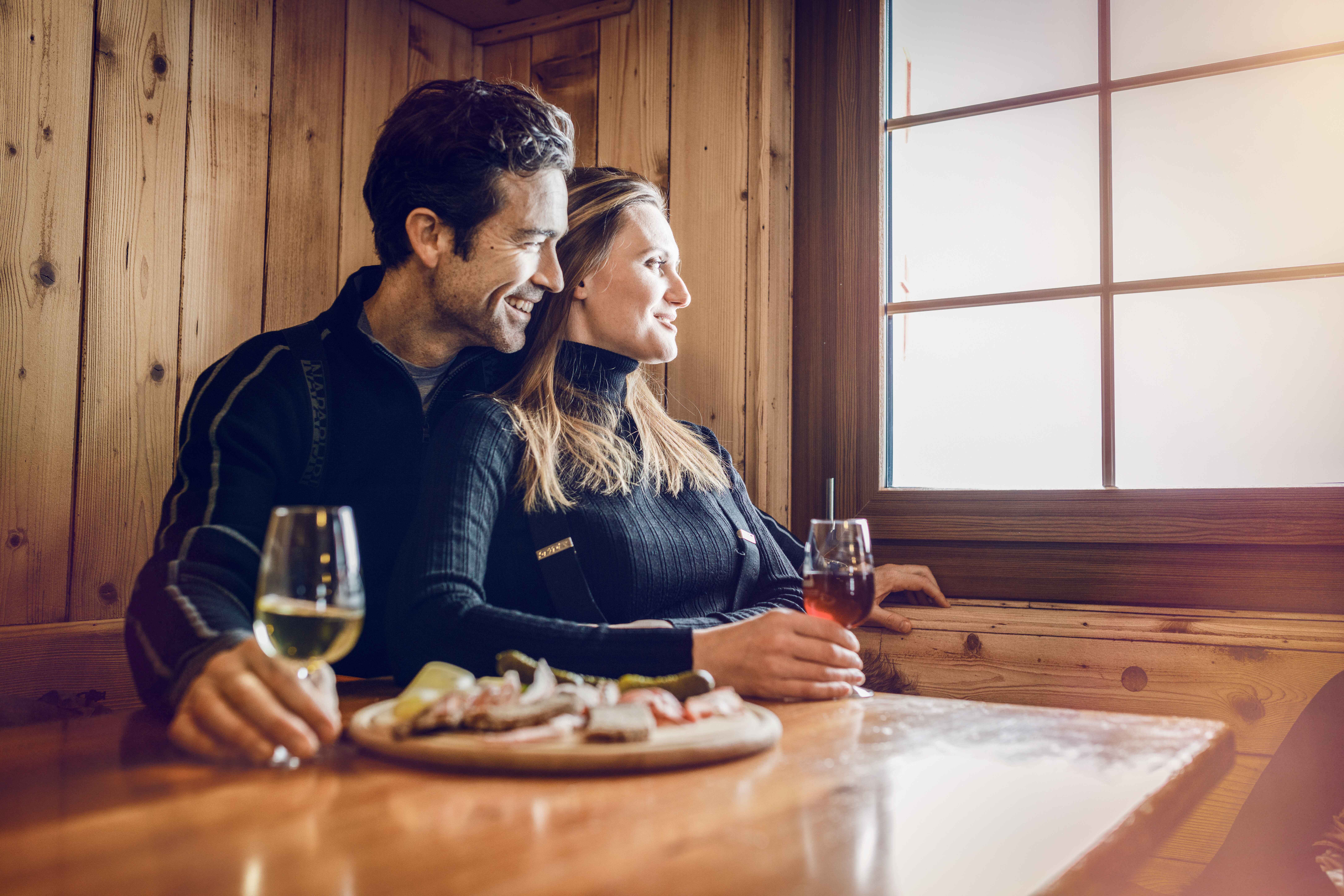 Un couple prend l'apéro (vin valaisan et planchette valaisanne) en observant la vue après une belle journée de ski sur les pistes de Crans-Montana. Valais, Suisse