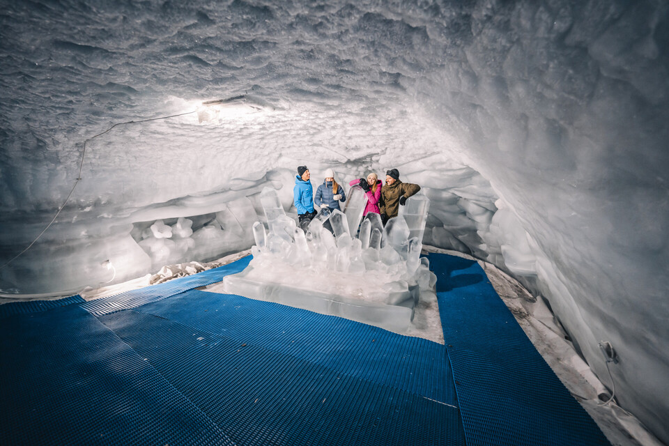 Un groupe de personnes posant sur une sculpture en forme de trône de glace à l’intérieur du Palais de glace de Zermatt