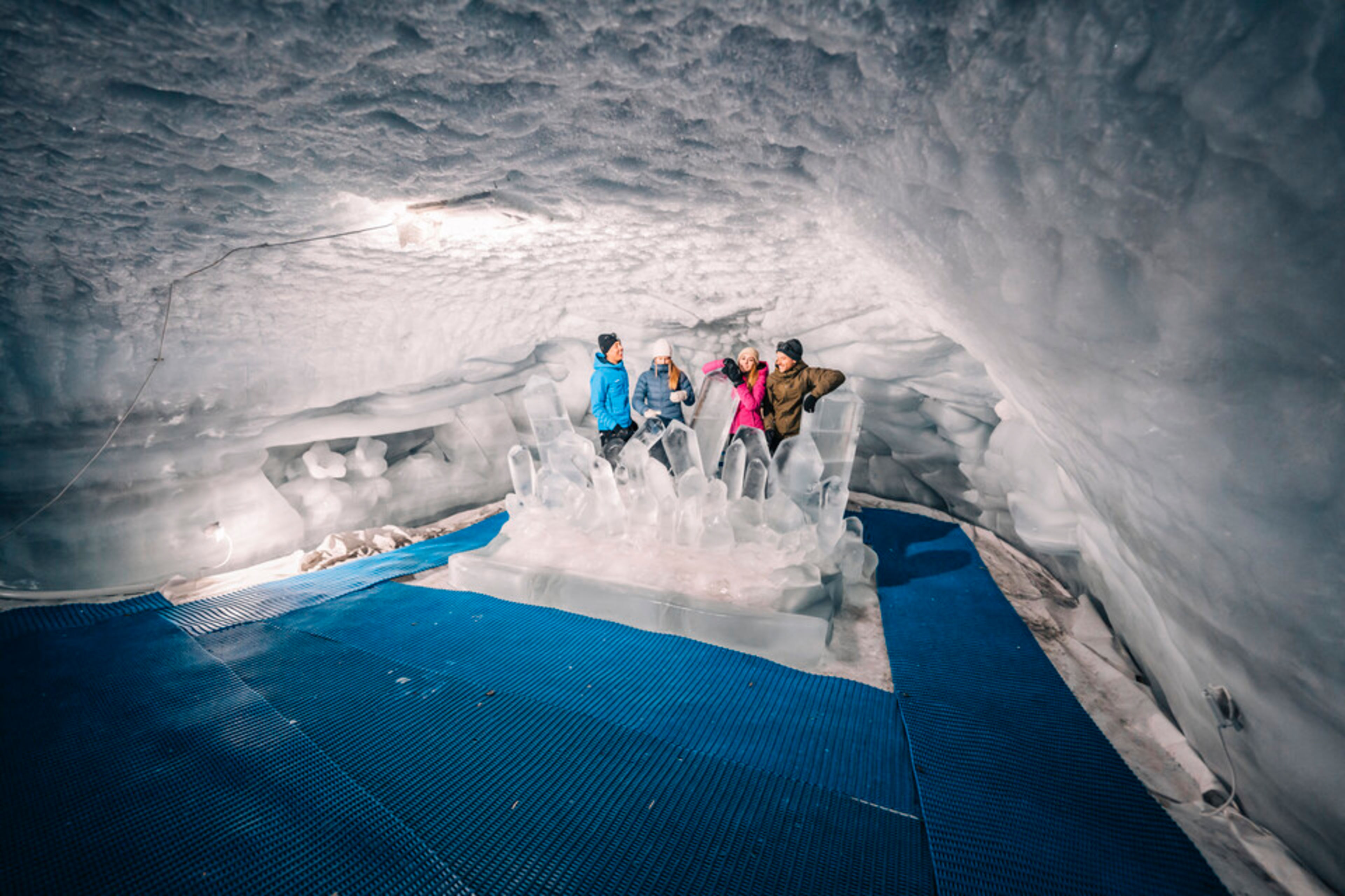 Un groupe de personnes posant sur une sculpture en forme de trône de glace à l’intérieur du Palais de glace de Zermatt