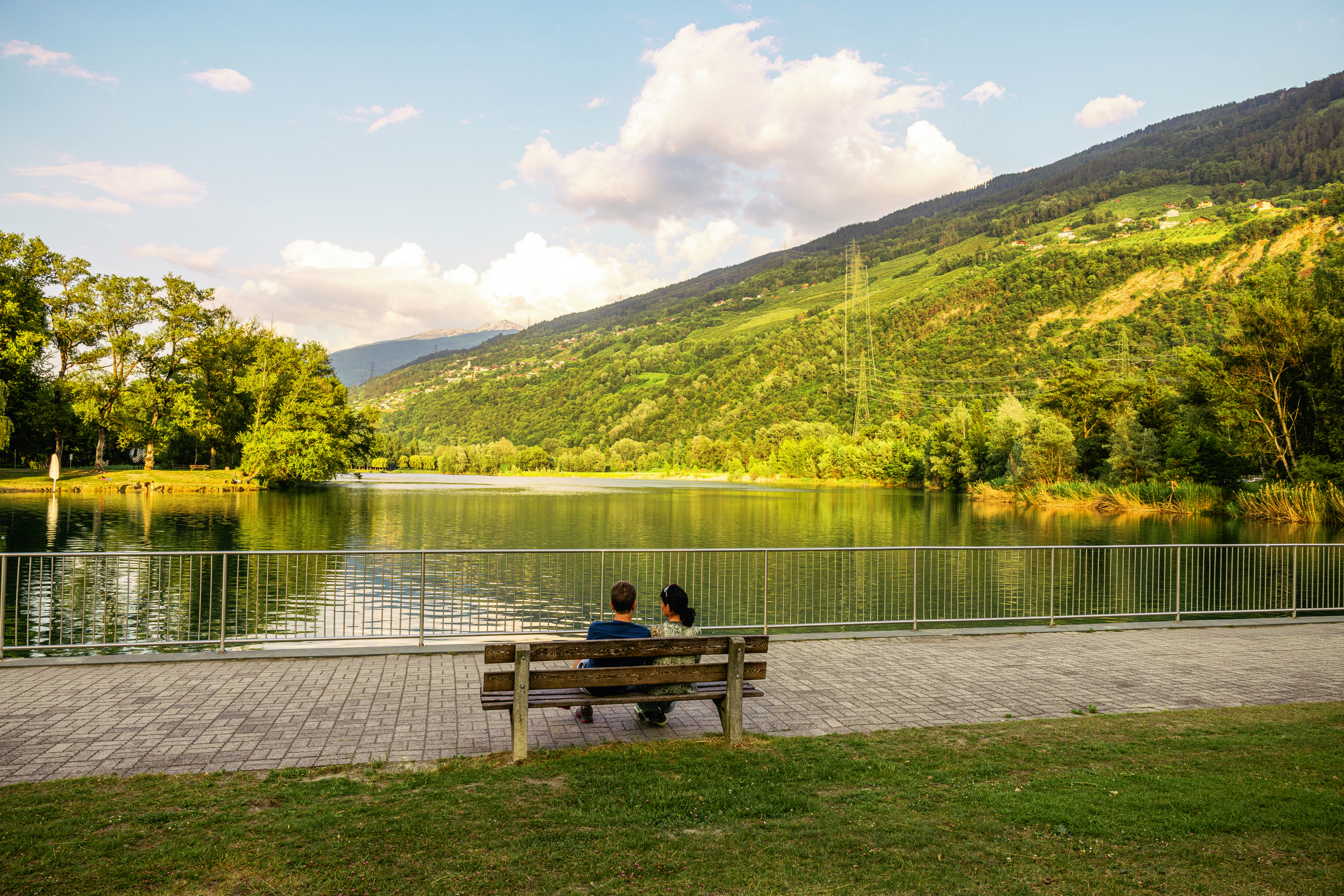 Couple assis sur un banc face au lac au Domaine des Îles à Sion, Valais, Suisse