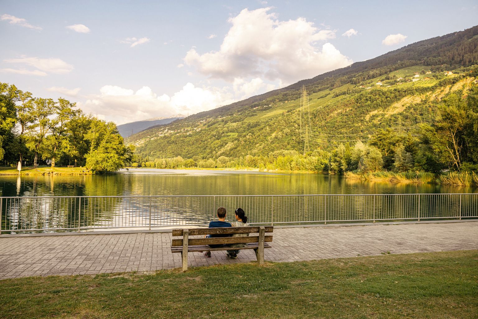 Couple assis sur un banc face au lac au Domaine des Îles à Sion, Valais, Suisse