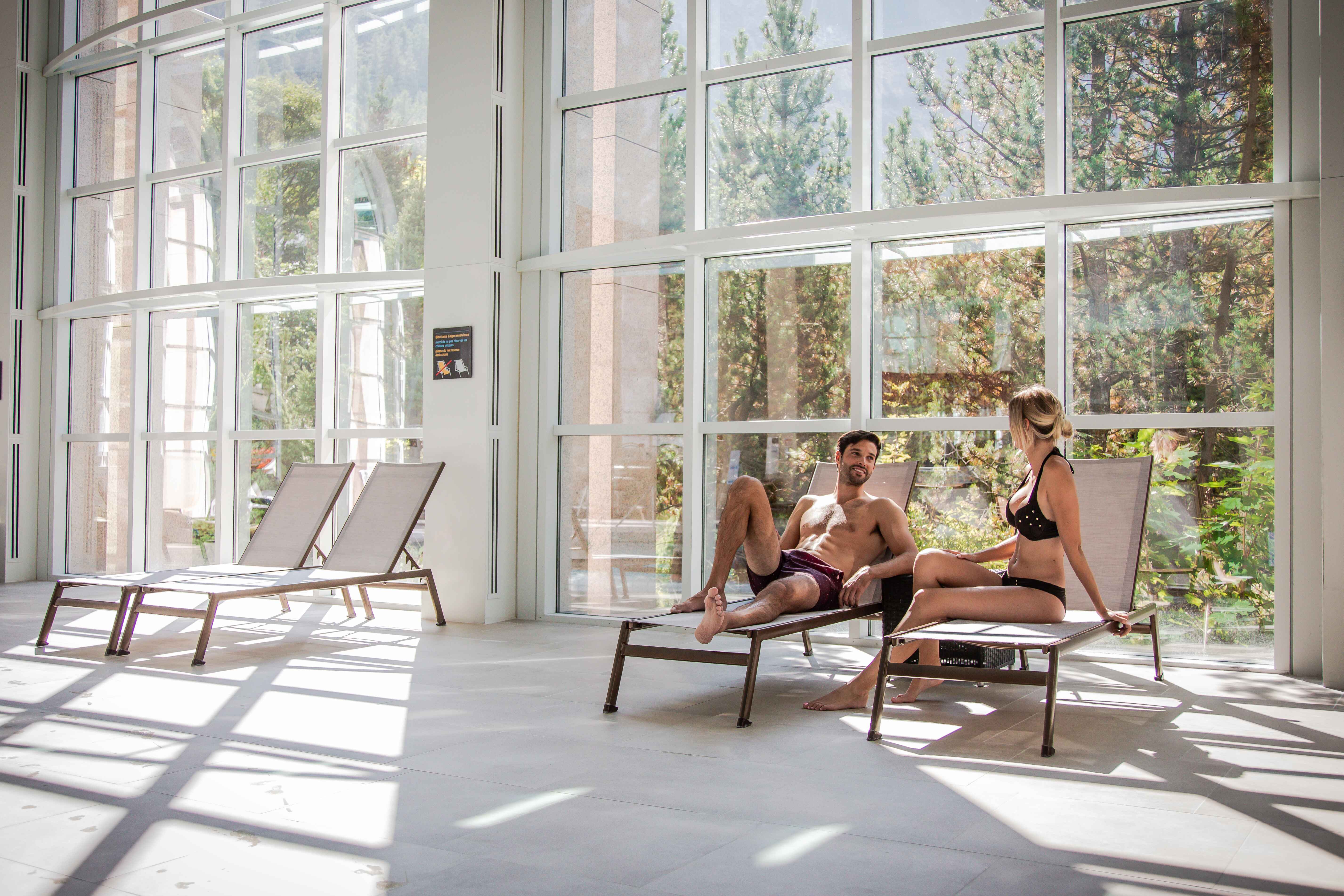 Deux personnes se détendent sur les transats à côté des bains thermaux à Leukerbad. Valais, Suisse