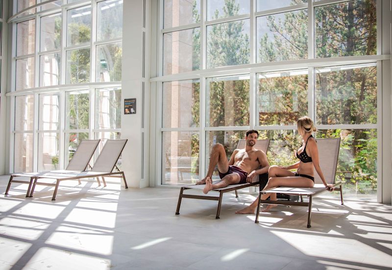 Deux personnes se détendent sur les transats à côté des bains thermaux à Leukerbad. Valais, Suisse