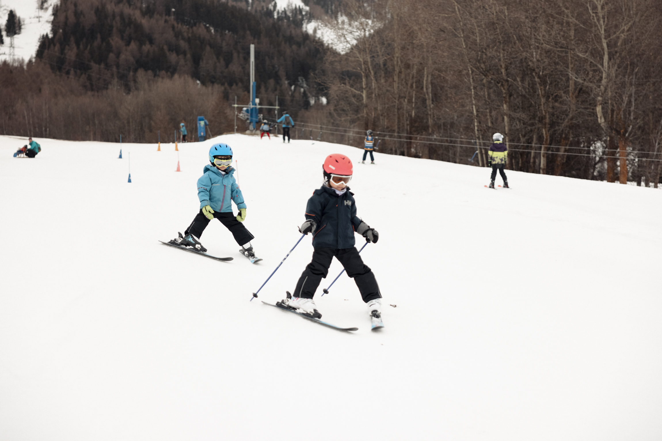Two children skiing in MoosAlbi Kids’ Paradise with ski instructor in the background