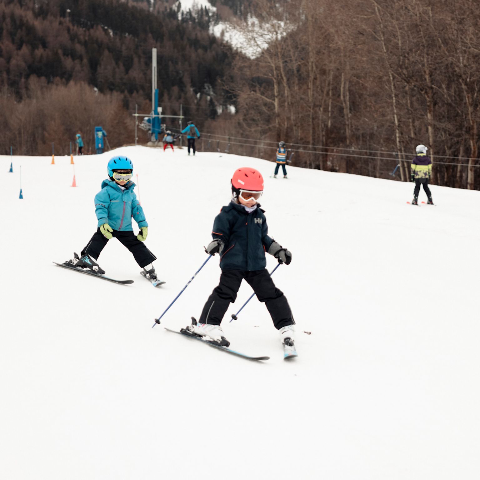 Two children skiing in MoosAlbi Kids’ Paradise with ski instructor in the background