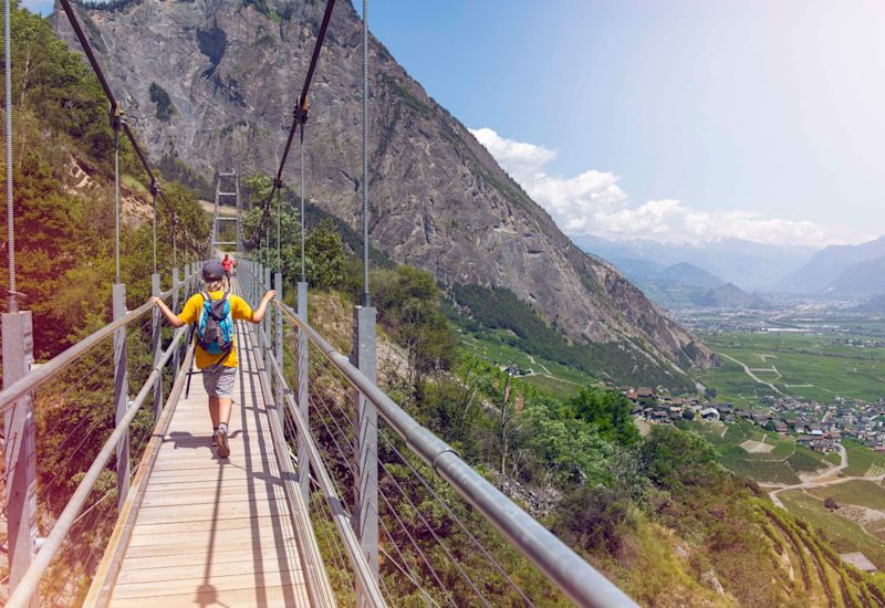 A young boy crosses the footbridge Farinet in Saillon. Valais, Switzerland