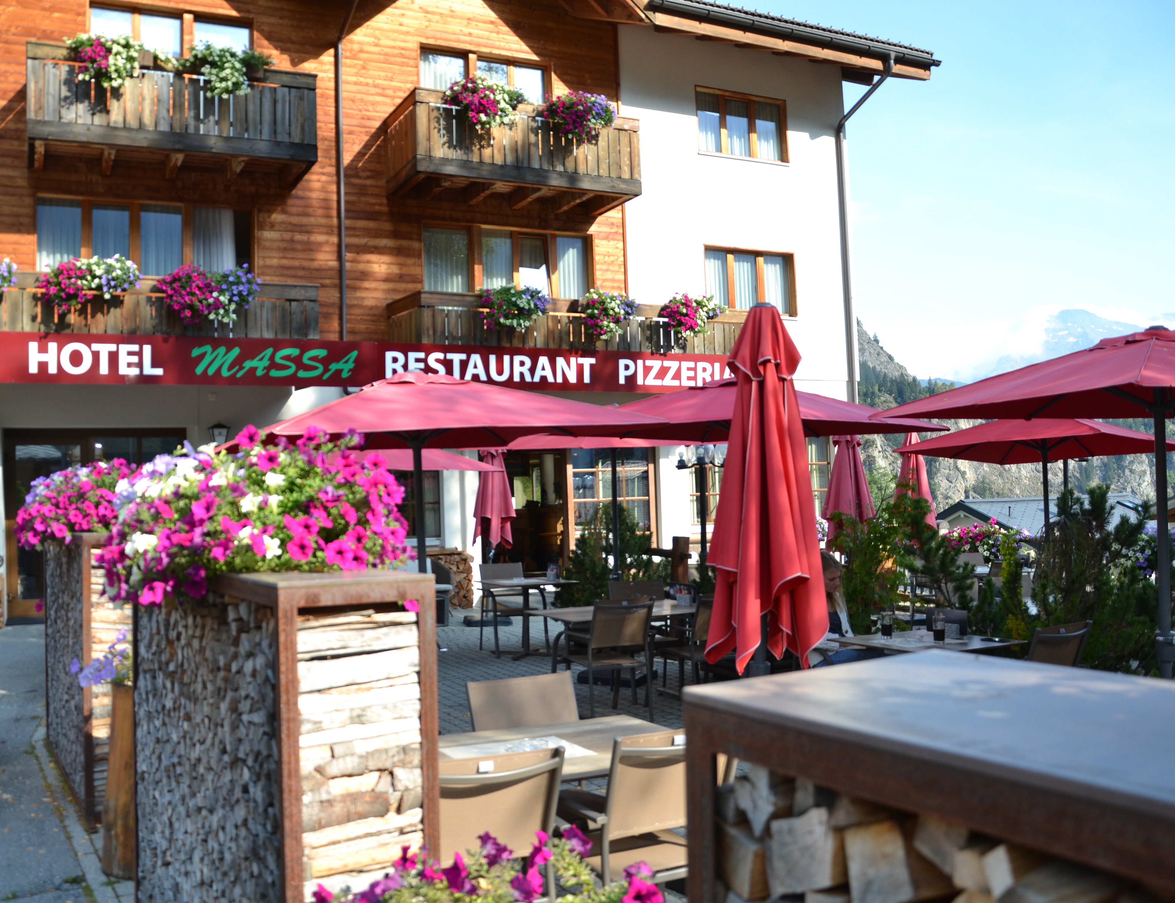 Terrasse des Hotels Massa in Blatten mit bunten Blumen und Blick auf die Alpen
