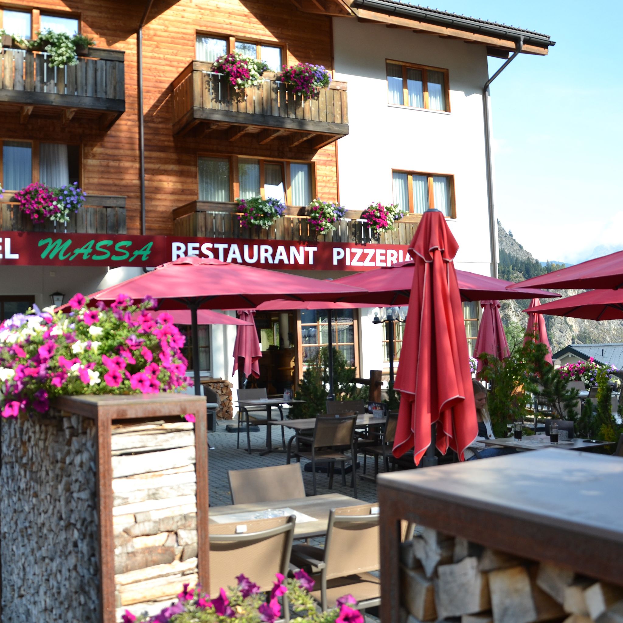 Terrasse des Hotels Massa in Blatten mit bunten Blumen und Blick auf die Alpen