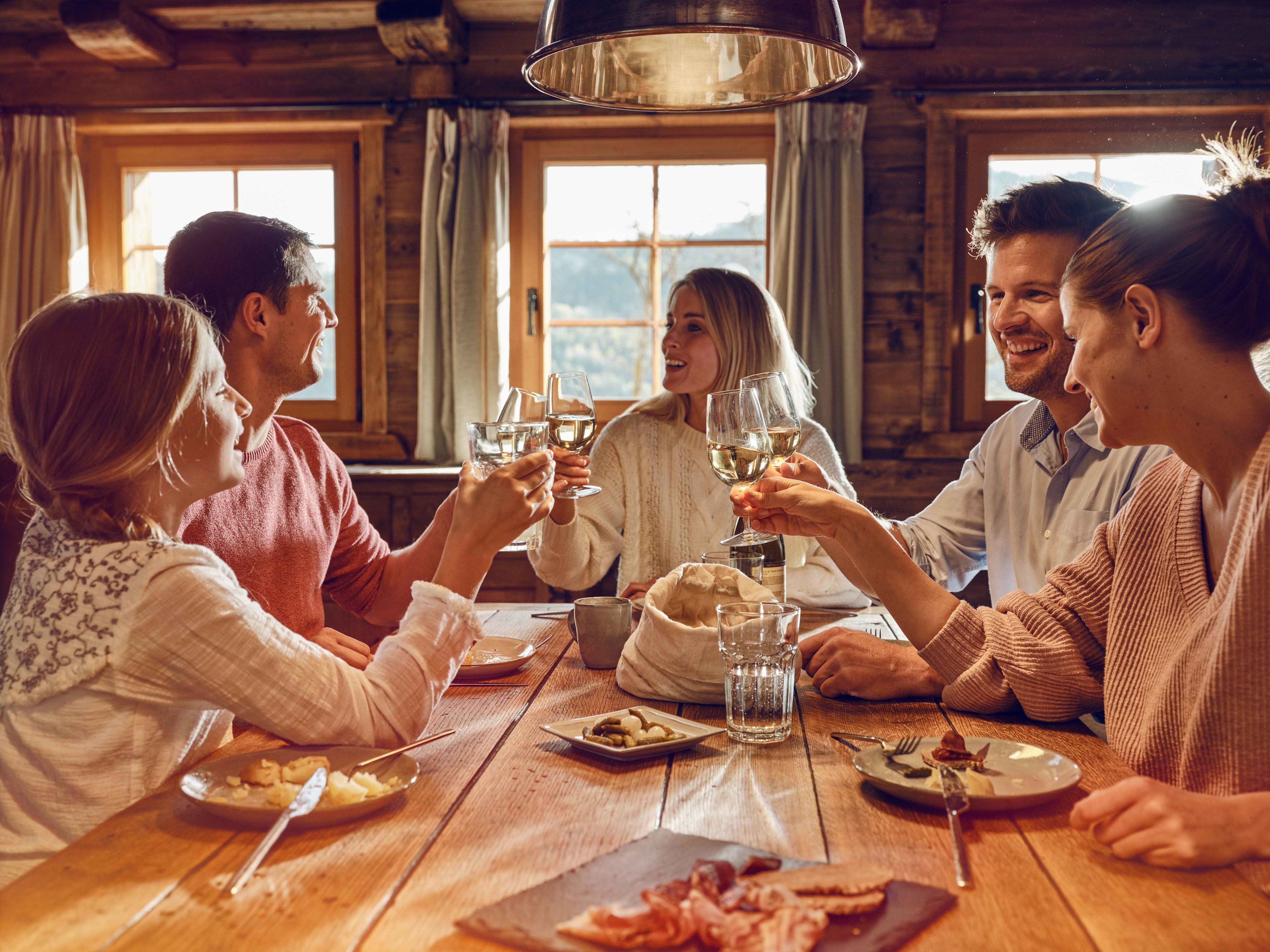 Des amis partagent un bon moment de convivialité autour d'une bonne raclette et du vin valaisan. Valais, Suisse
