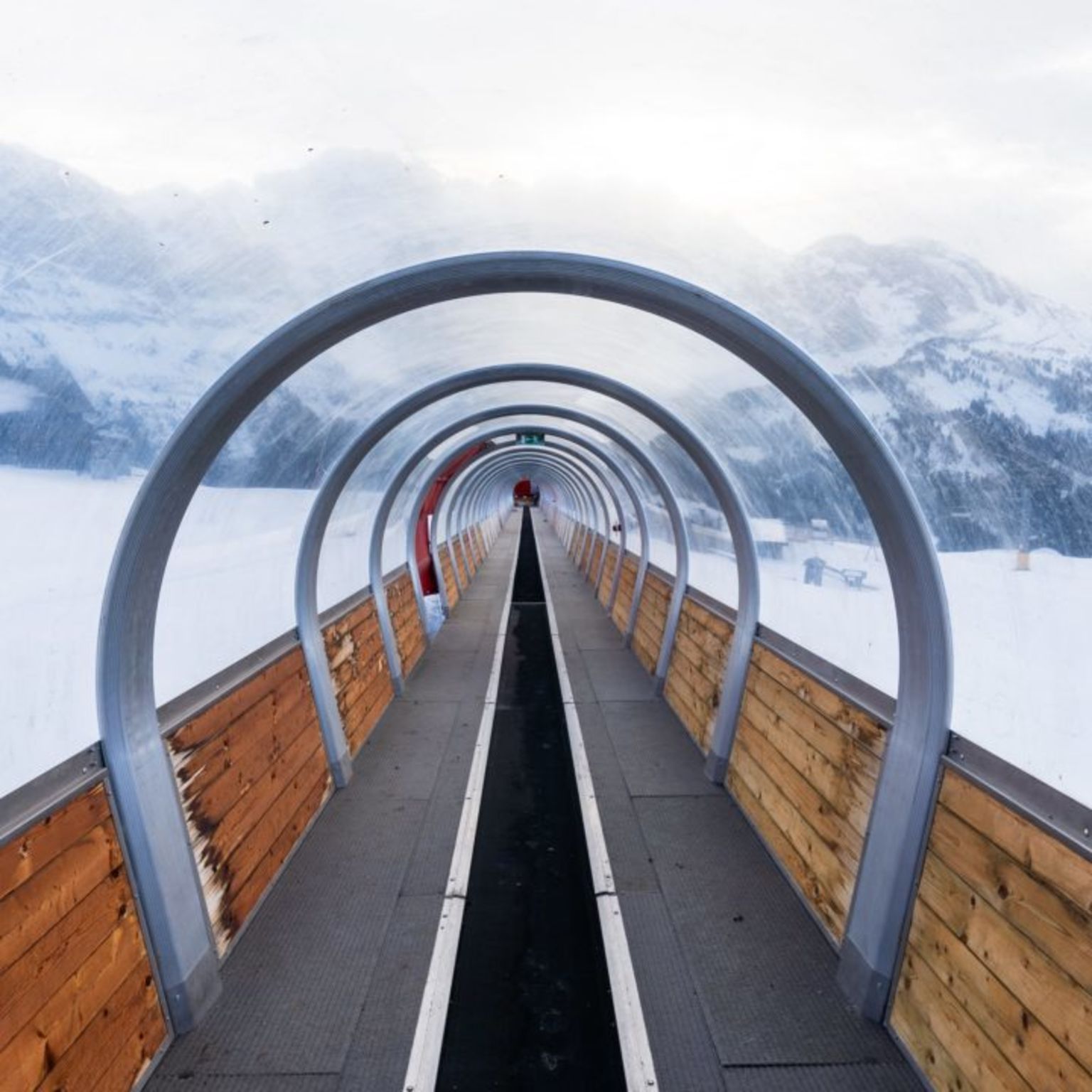Blick durch den überdachten Zauberteppich in Champéry, im Skigebiet Portes du Soleil, mit verschneiten Bergen im Hintergrund.