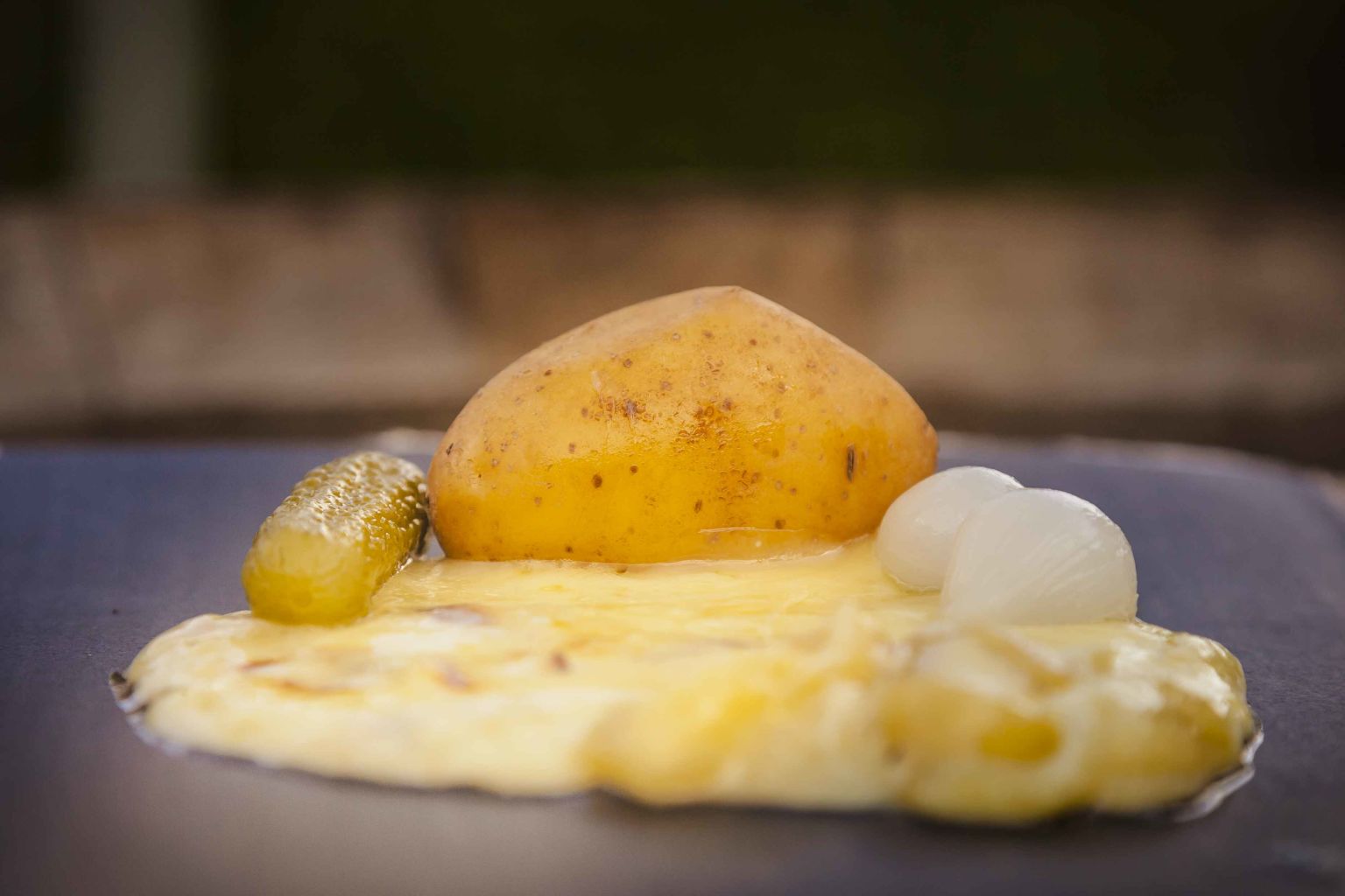 Ein Raclette mit einer Kartoffel, Zwiebeln und Cornichons, Wallis, Schweiz