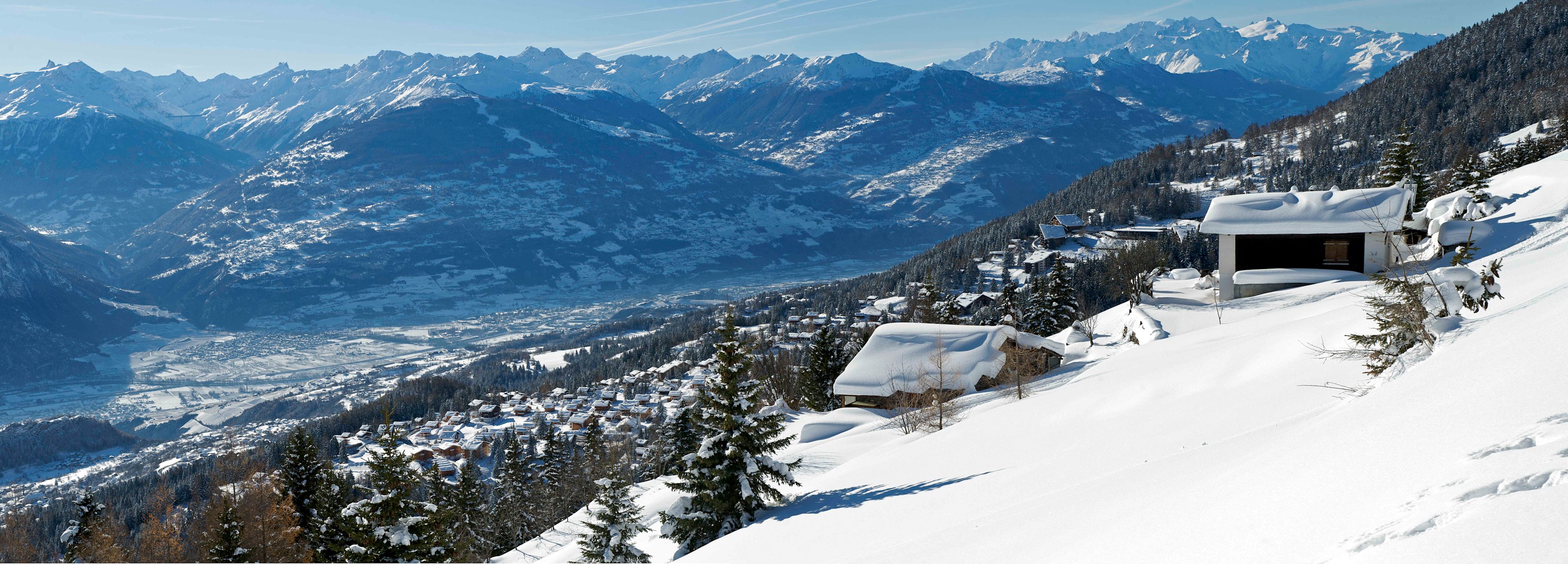 Das verschneite Anzère mit seinen Maiensässen, die Walliser Alpen und das Montblanc-Massiv im Hintergrund.