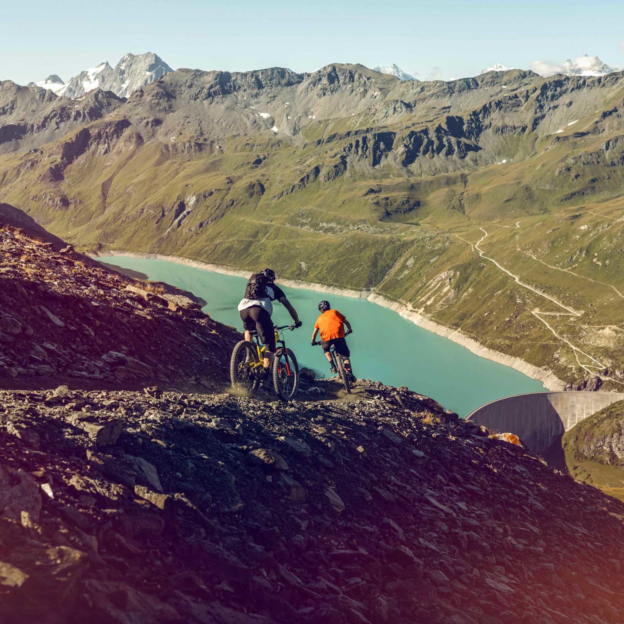 Zwei Mountainbiker bei der Abfahrt einer Mountainbike-Route mit Blick auf den Lac de Moiry. Wallis, Schweiz