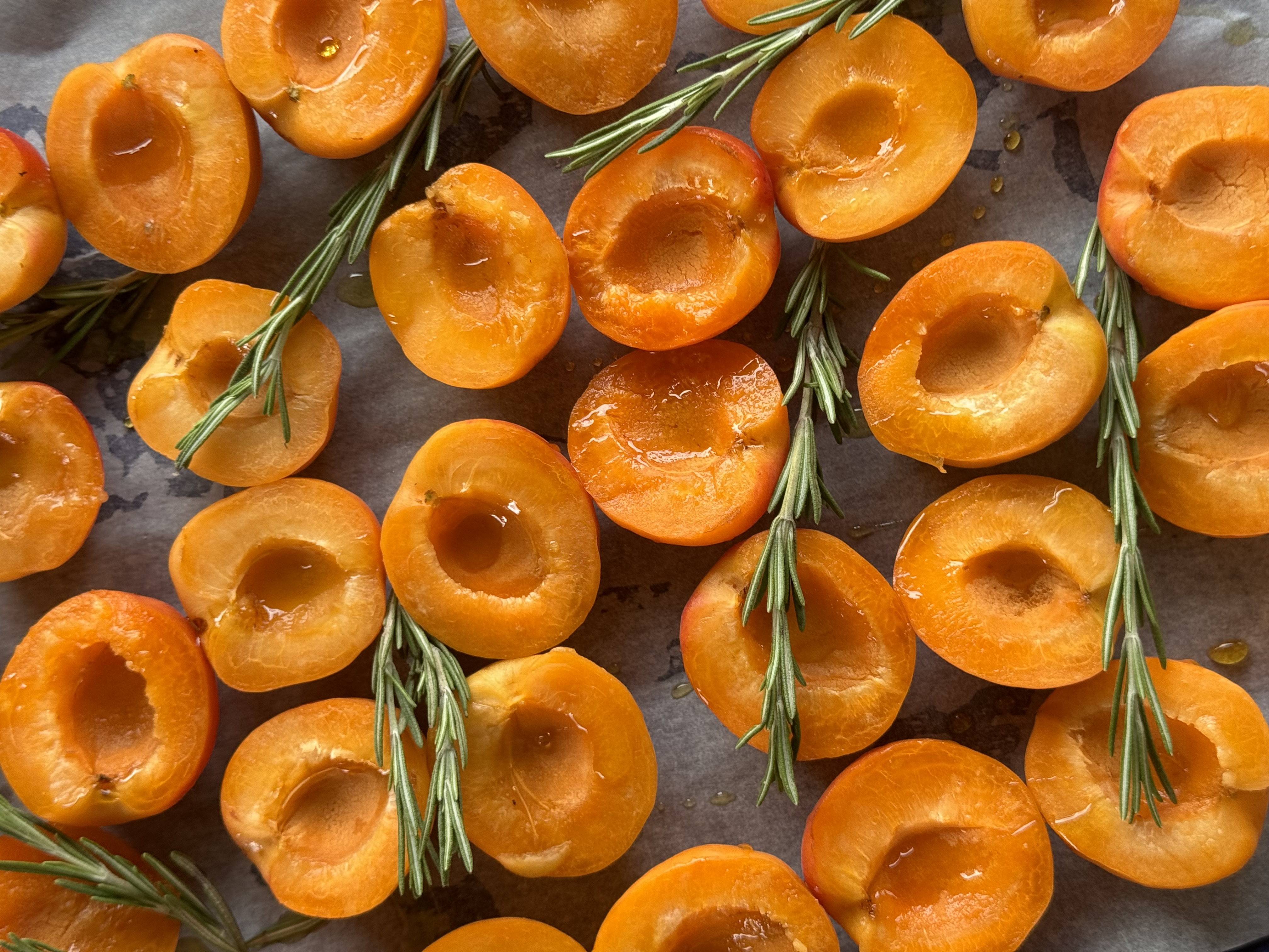 Halved Valais apricots and rosemary sprigs before baking