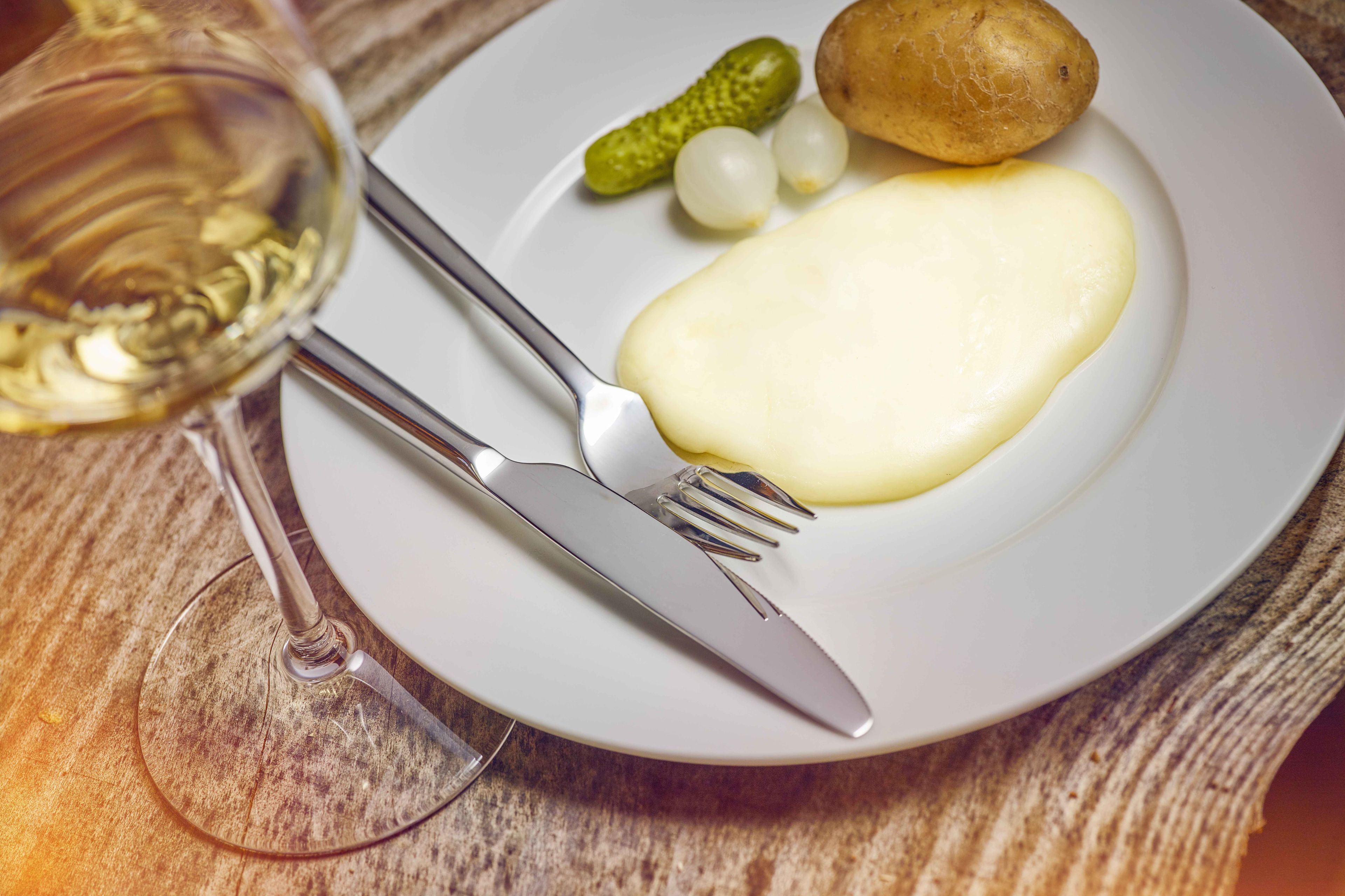 Melted raclette cheese with potatoes, gherkins and onions in Valais, Switzerland