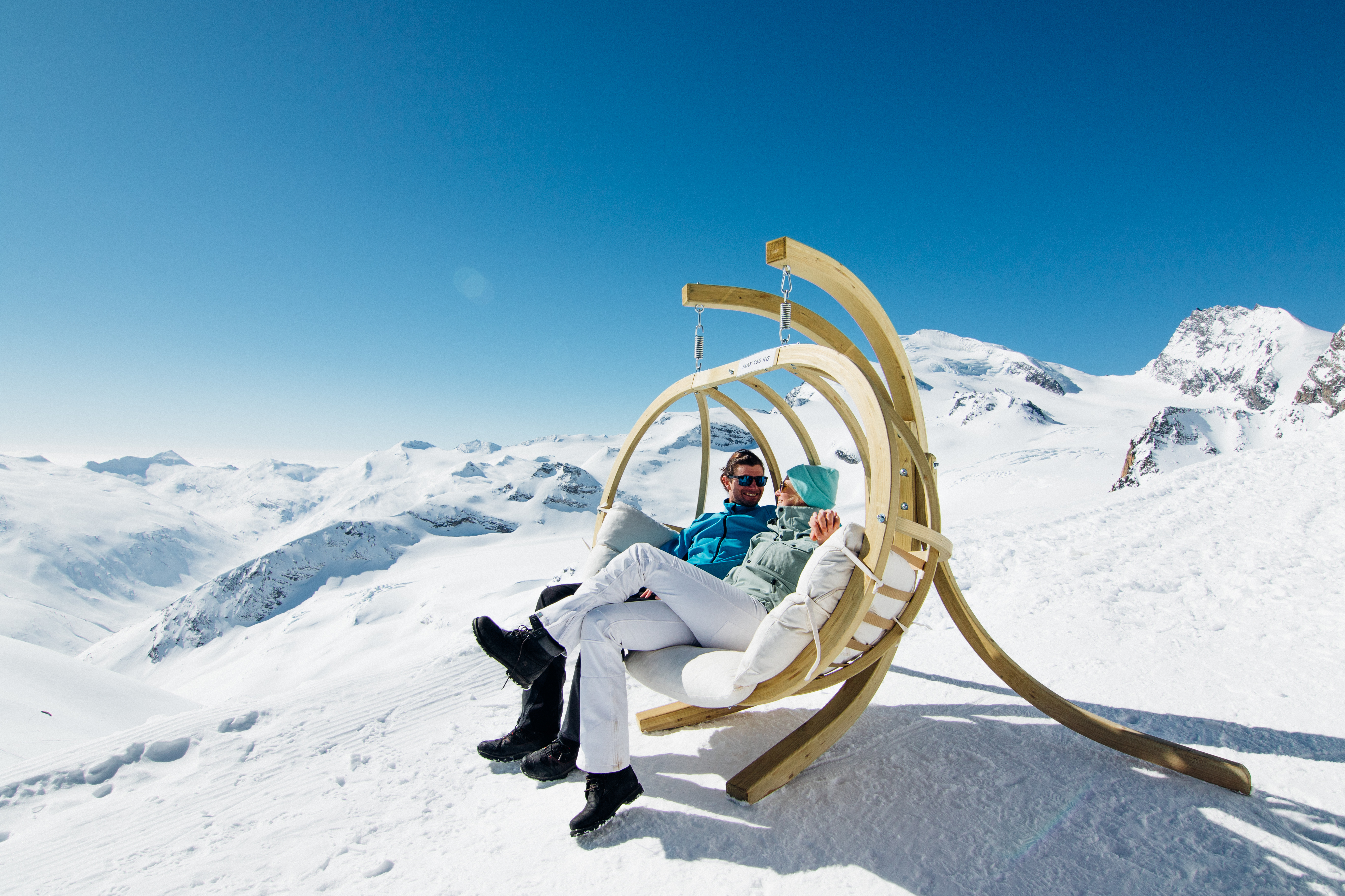 Un couple se repose et discute au sommet des pistes de ski de Sass-Fee en plein hiver dans les Alpes valaisannes. Valais, Suisse