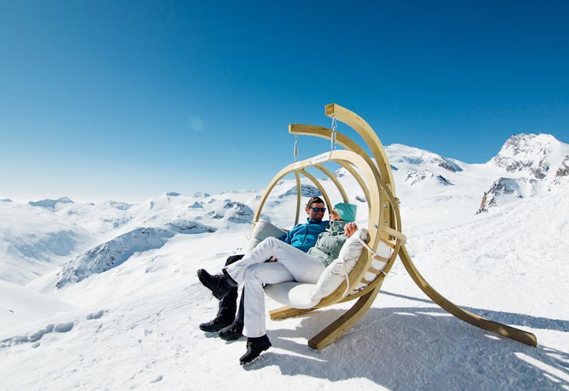 Un couple se repose et discute au sommet des pistes de ski de Sass-Fee en plein hiver dans les Alpes valaisannes. Valais, Suisse