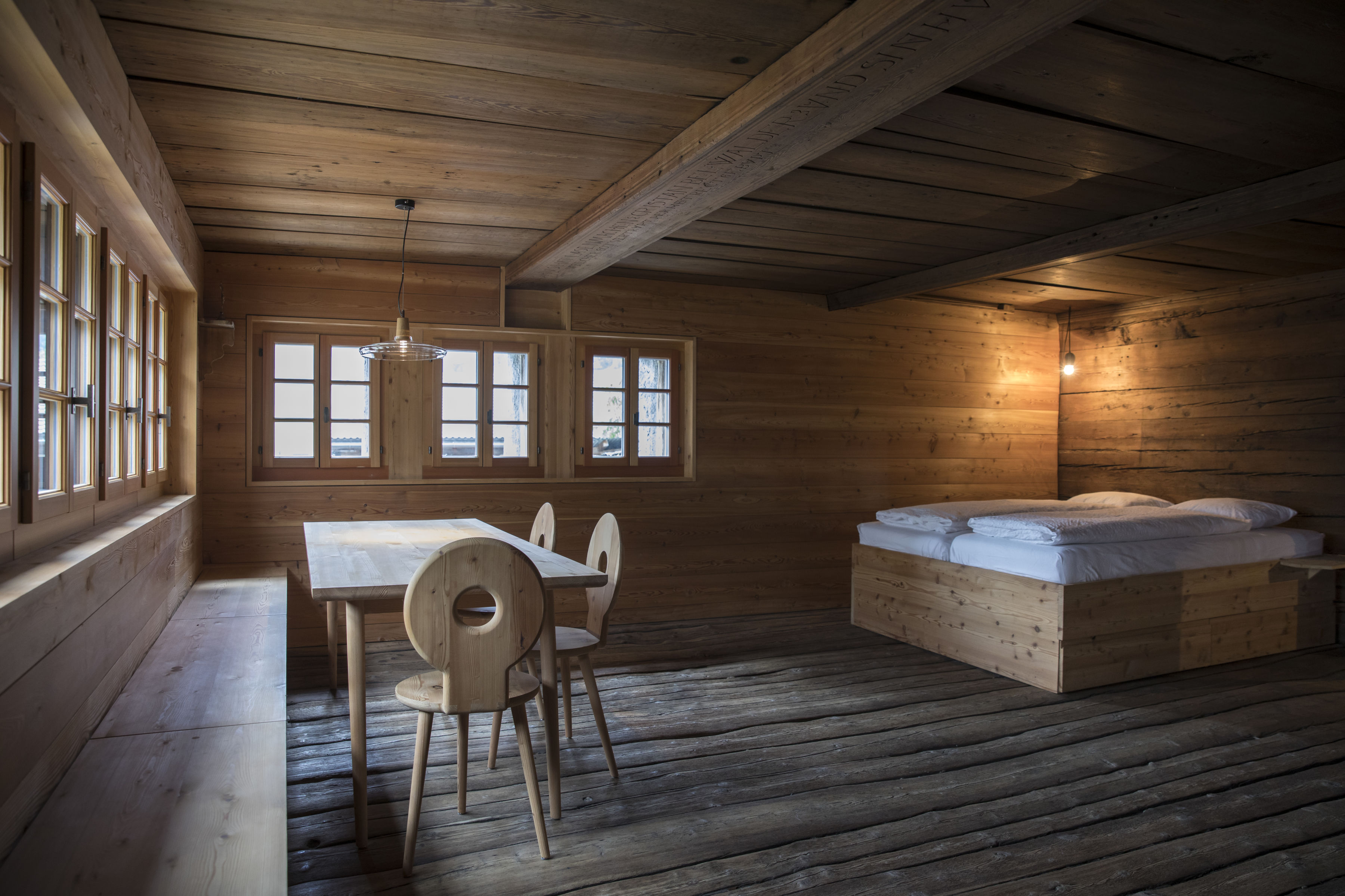 Renovated chalet with bed, chairs and wooden table. Valaisan furniture Valais Wallis Schweiz Switzerland Suisse