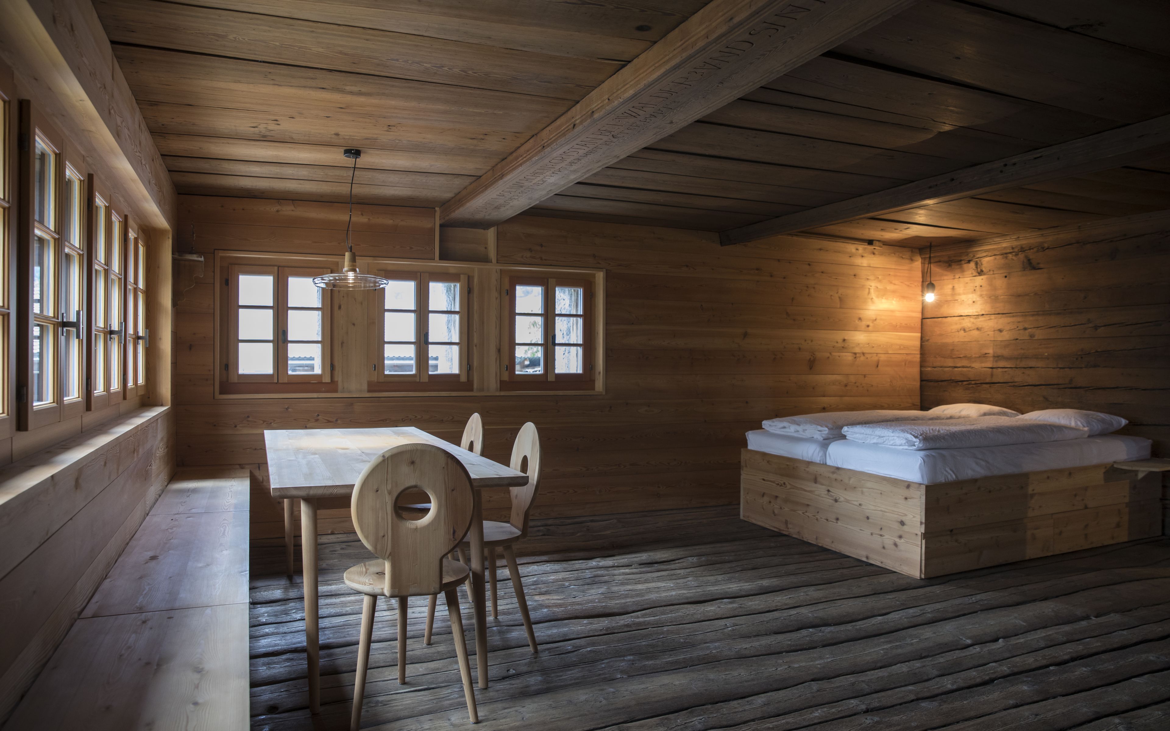Chalet renové avec lit, chaises et table en bois. Meubles valaisans Valais Wallis Schweiz Switzerland Suisse