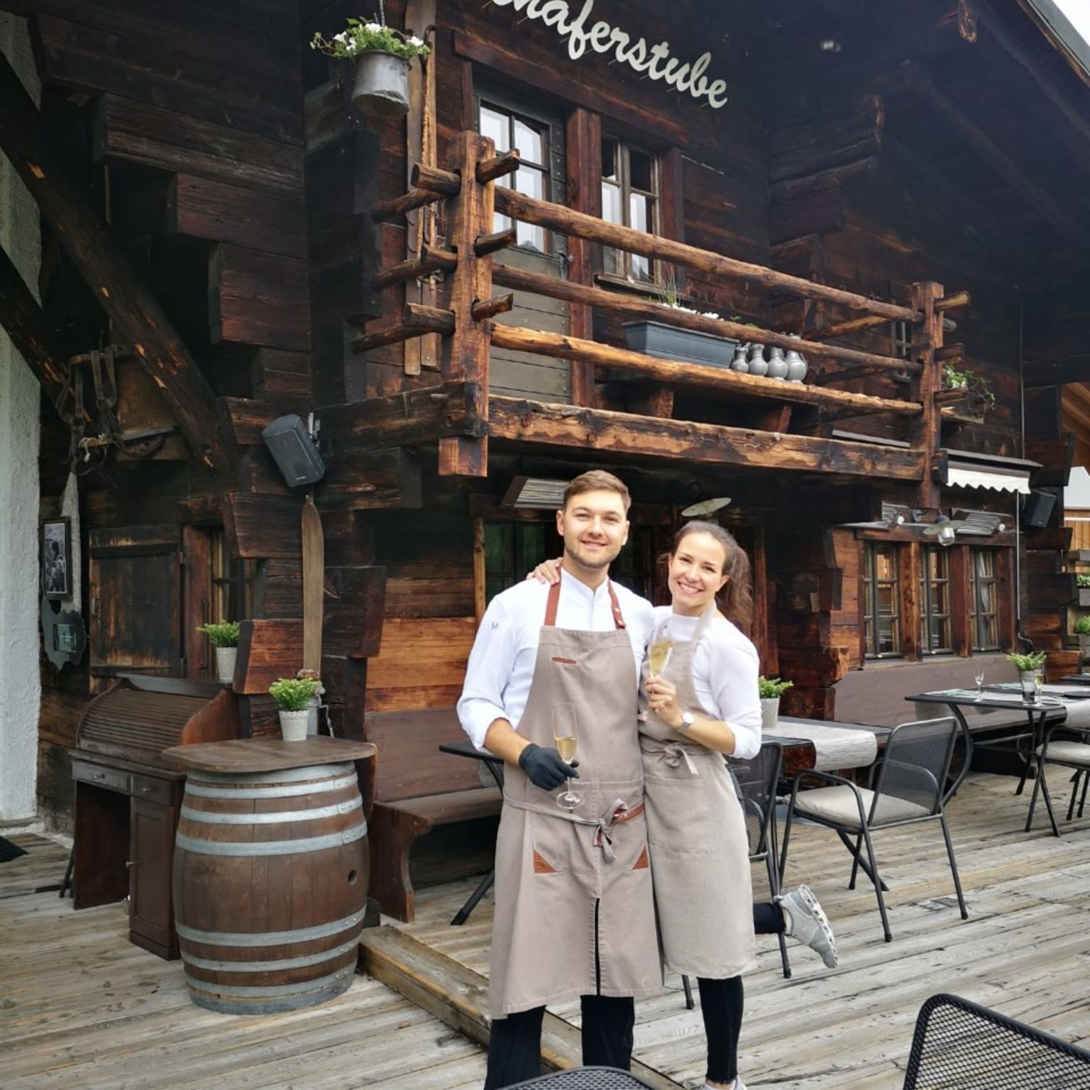 The Schäferstube restaurant in Saas-Fee, Valais, with its traditional wooden facade and hosts on the sunny terrace