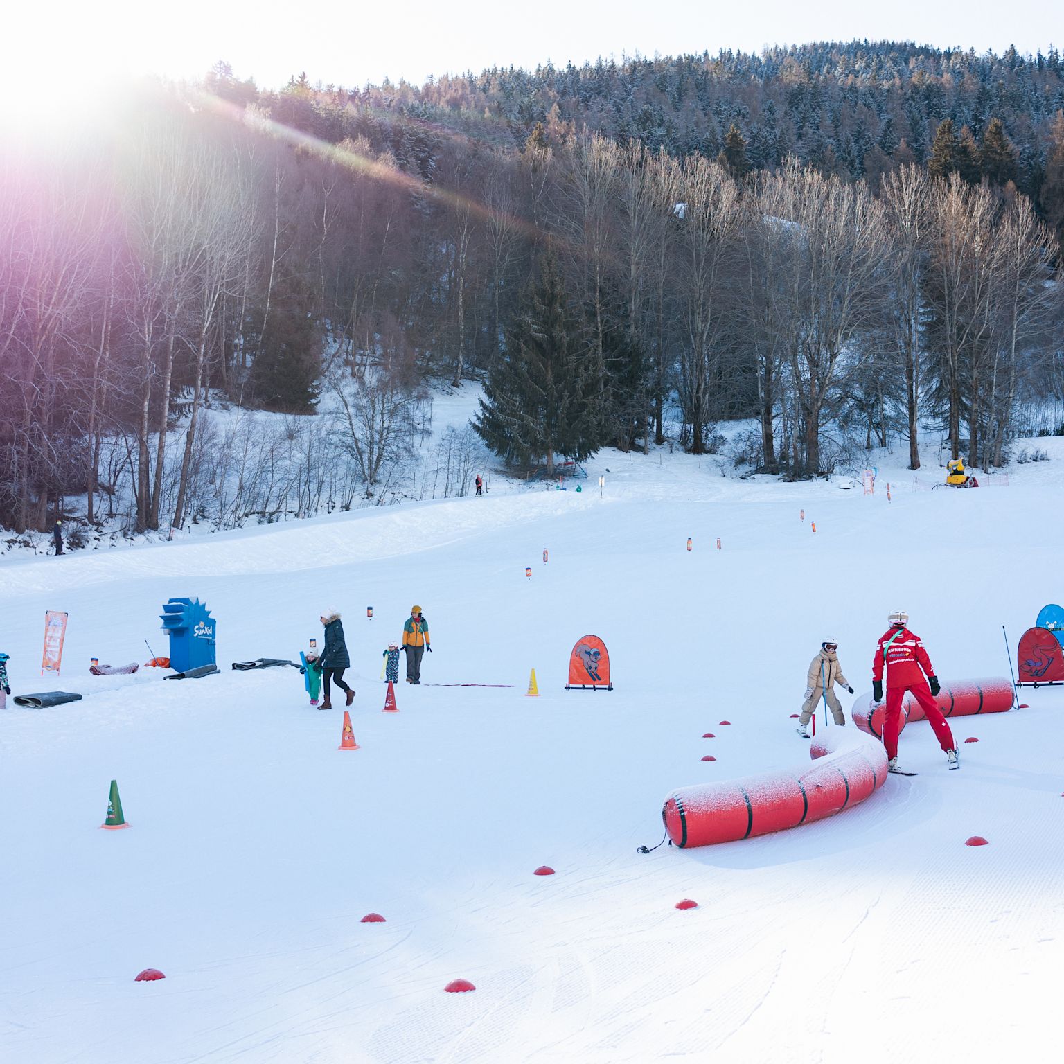 Ski instructor and beginners practicing skiing in the Le Lavioz beginner area in Vercorin, surrounded by a snowy winter landscape.