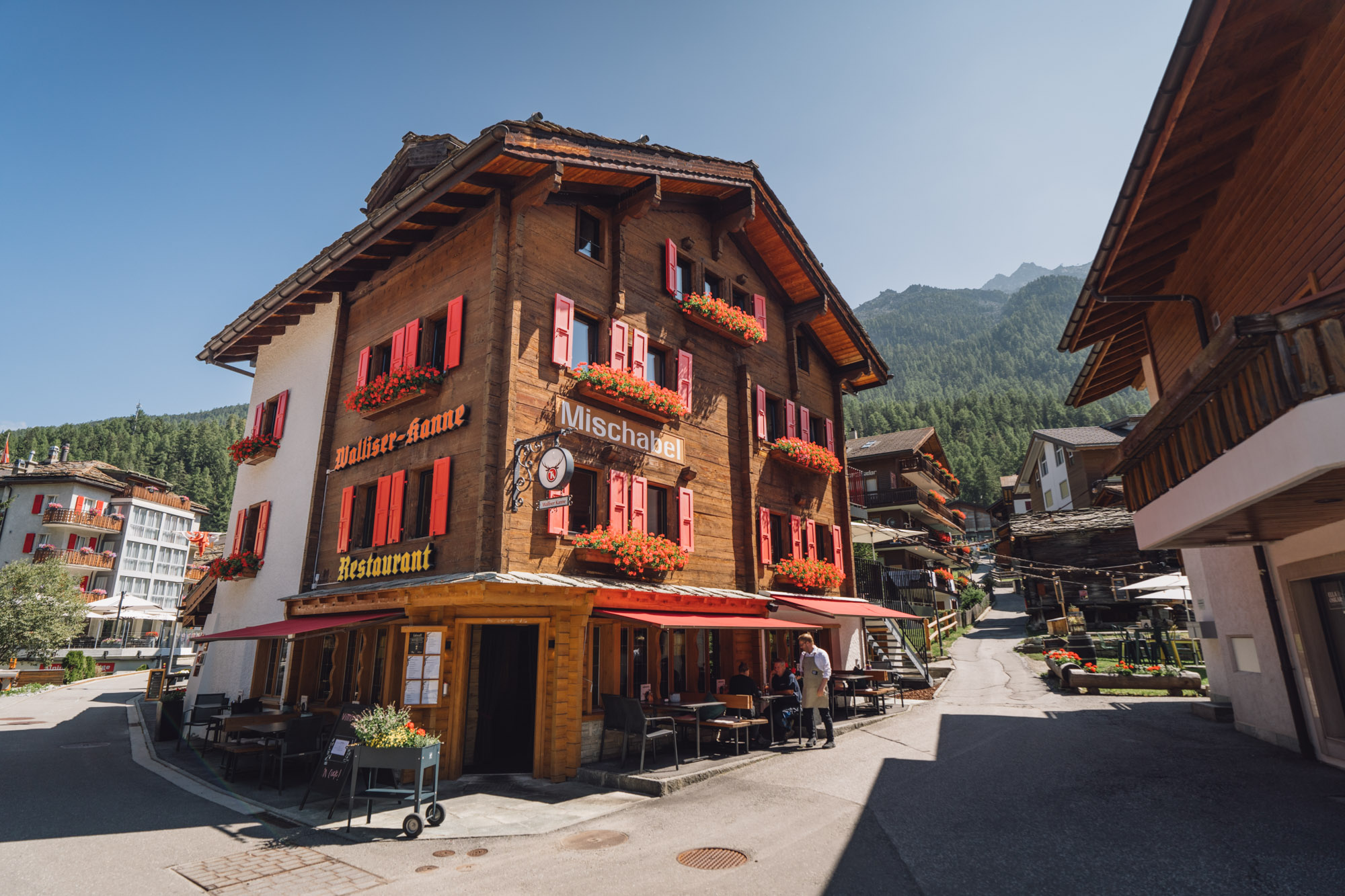 Traditionelles Boutique-Hotel Walliserkanne mit roten Fensterläden und Restaurantterrasse in Grächen