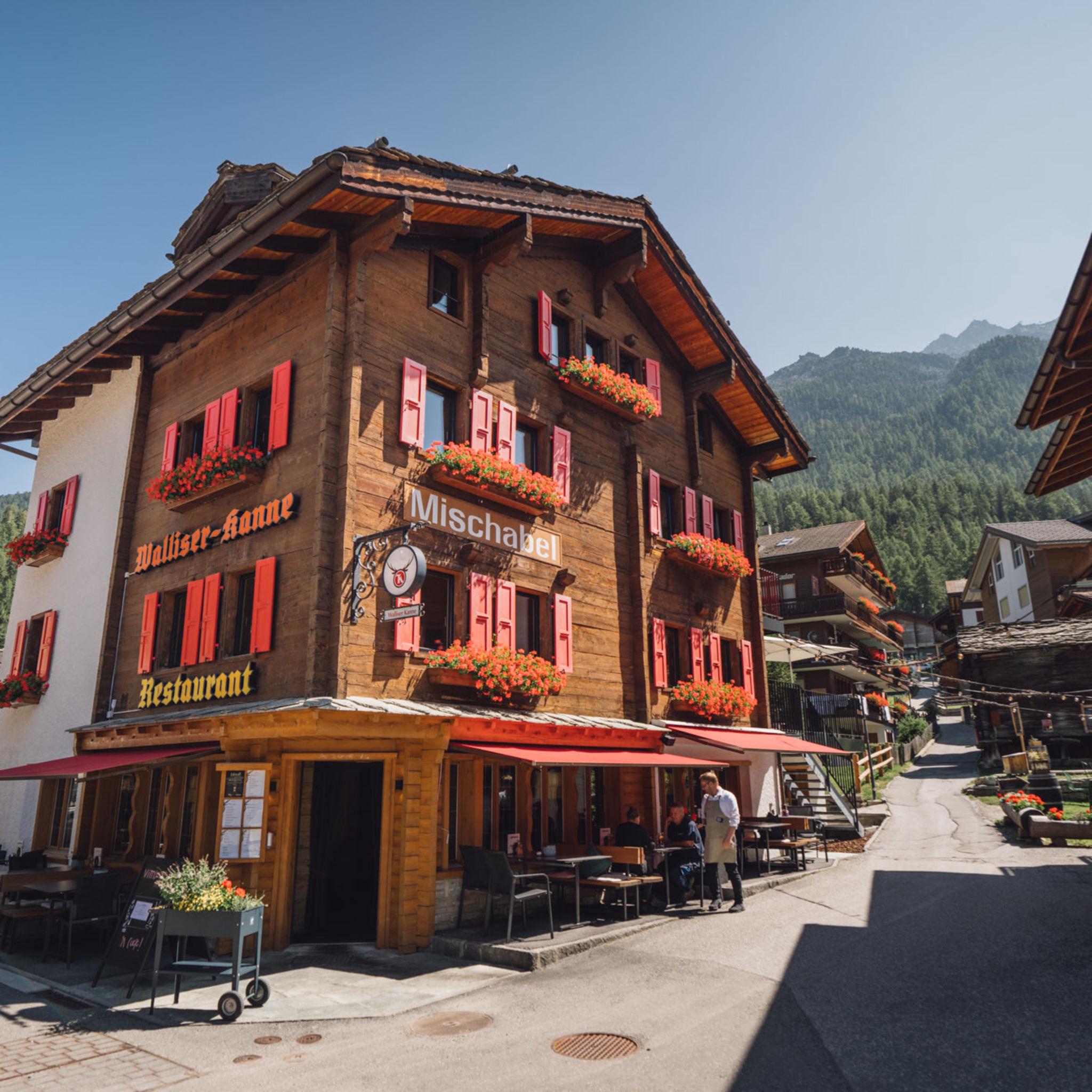 Traditionelles Boutique-Hotel Walliserkanne mit roten Fensterläden und Restaurantterrasse in Grächen