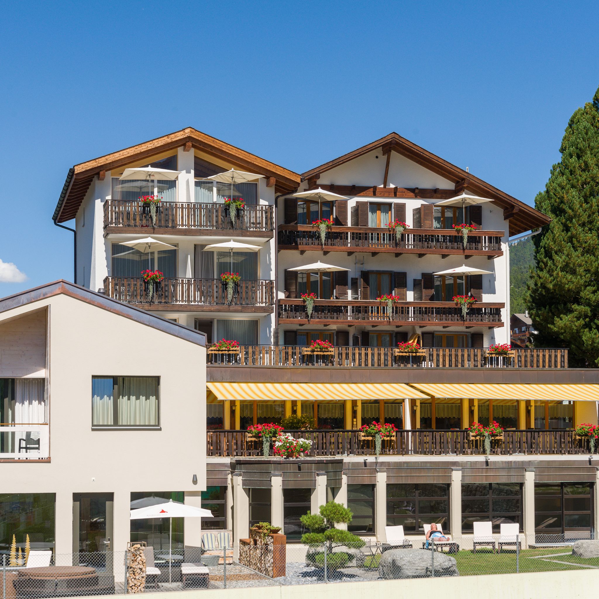 Aussenansicht des Aktiv Hotel & Spa Hannigalp in Grächen mit Terrasse und Blumenschmuck