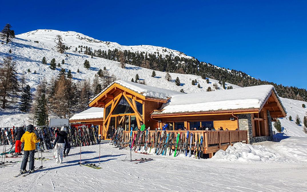 Restaurant Le Hameau de Tortin sur les pistes de ski à Nendaz, Valais, avec des skieurs devant