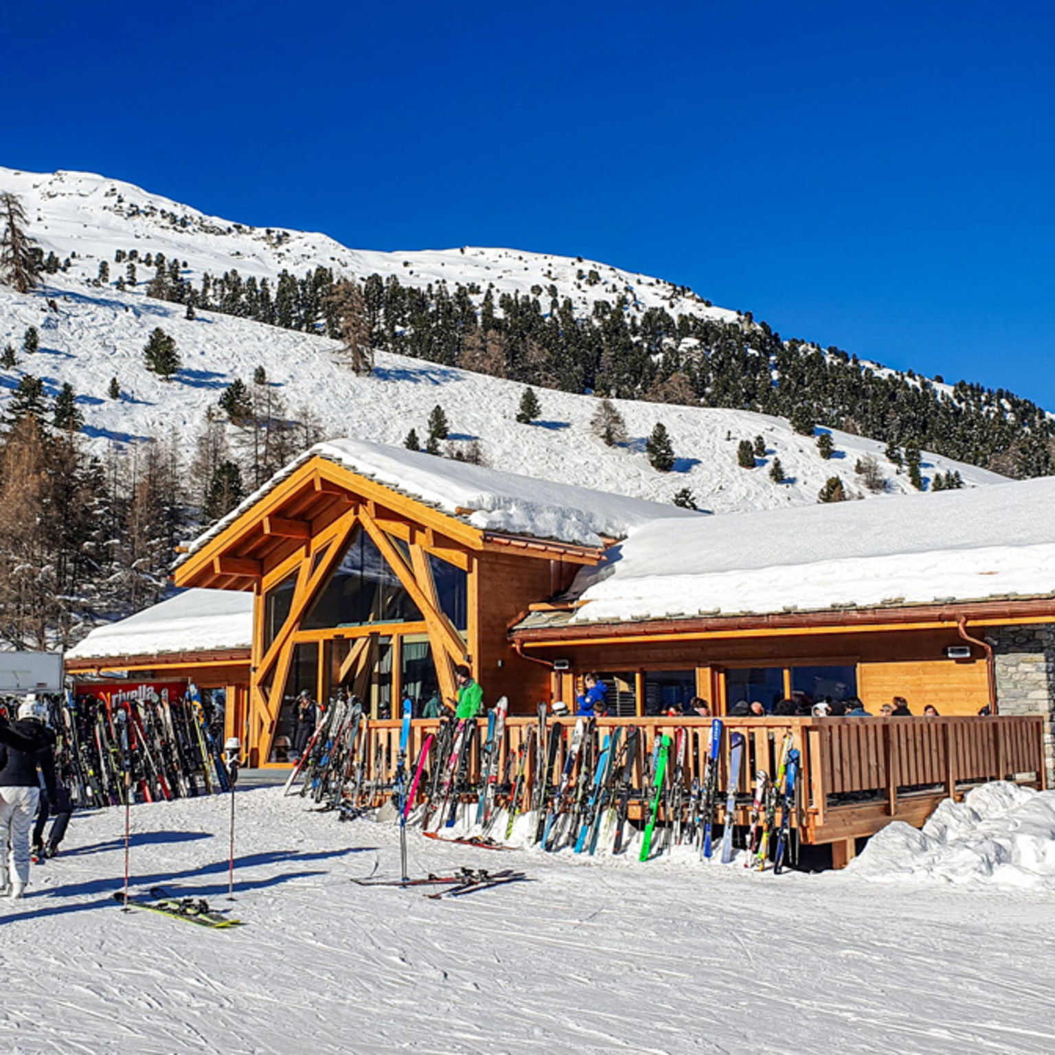 Le Hameau de Tortin restaurant on the ski slope in Nendaz, Valais, with skiers in front